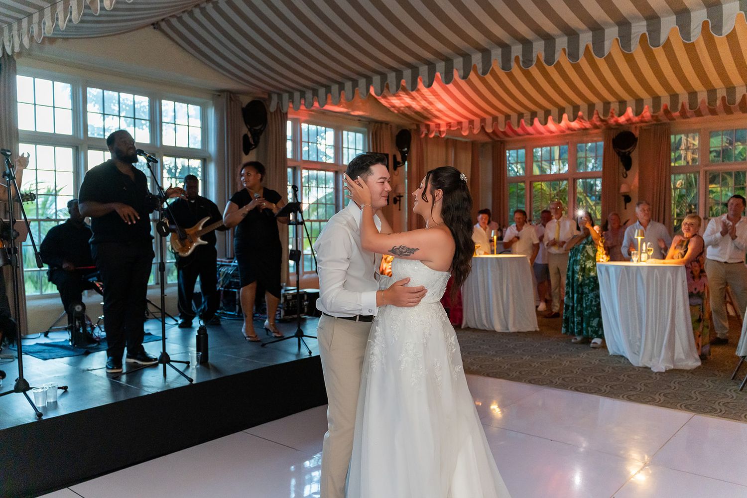 Bride and groom share first dance at wedding reception with live band performing in elegant venue.