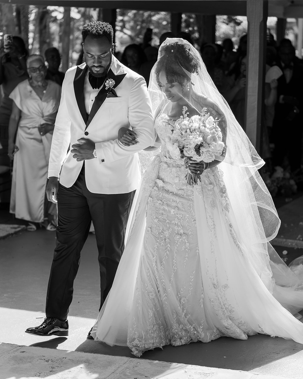 Black and white photo of bride and groom walking down the aisle at their outdoor wedding ceremony.