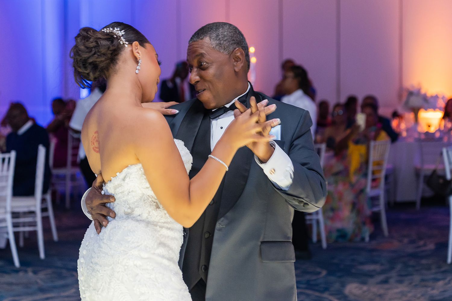 Bride and father share an emotional first dance at wedding reception with blue uplighting.