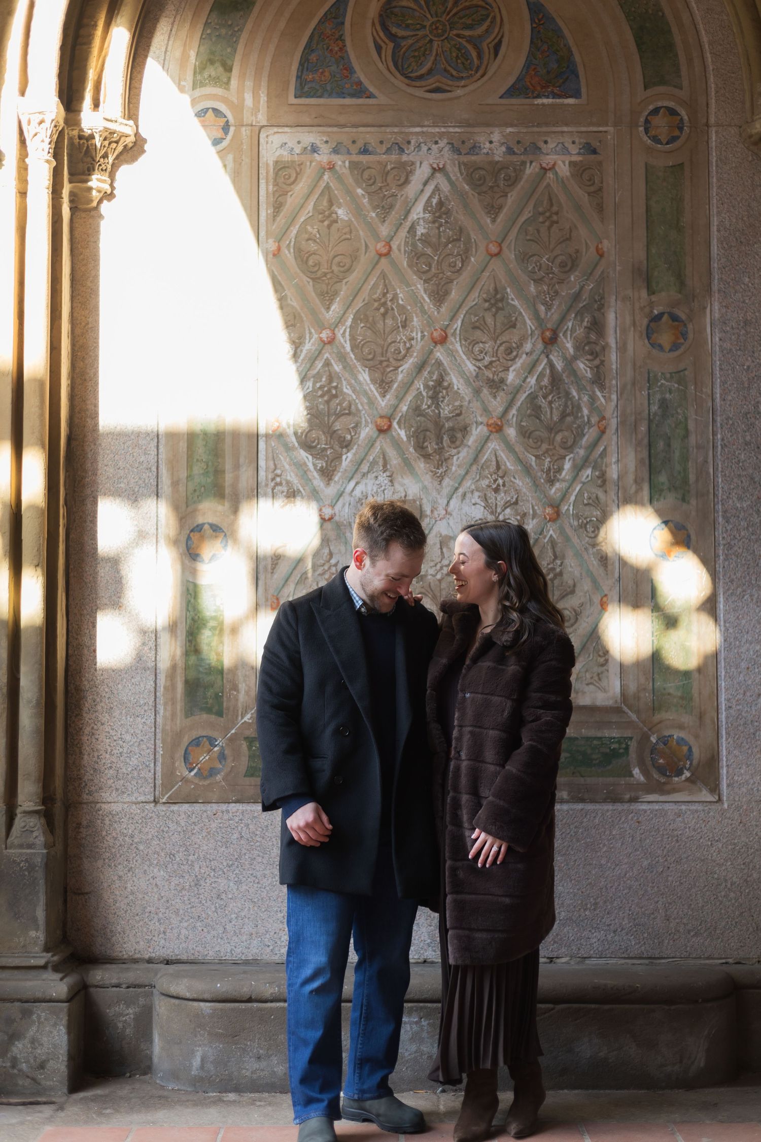 Two people stand together under an archway of Bethesda Terrace