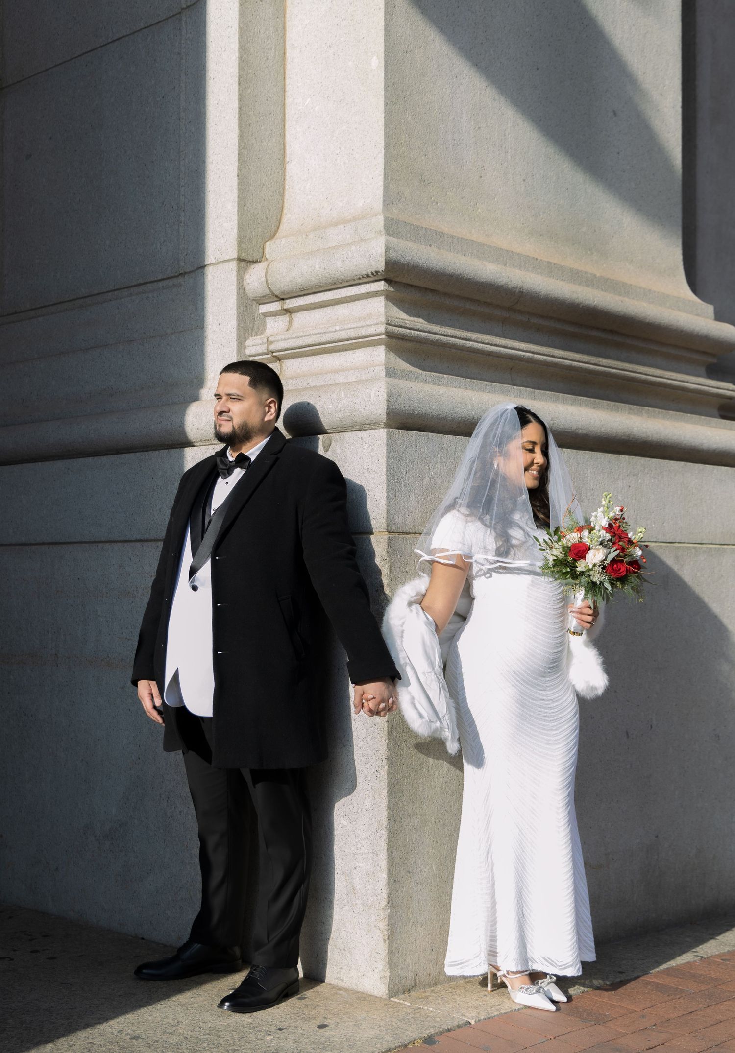 Couple holding hands behind the NYC Supreme Court building taking portraits before their ceremony