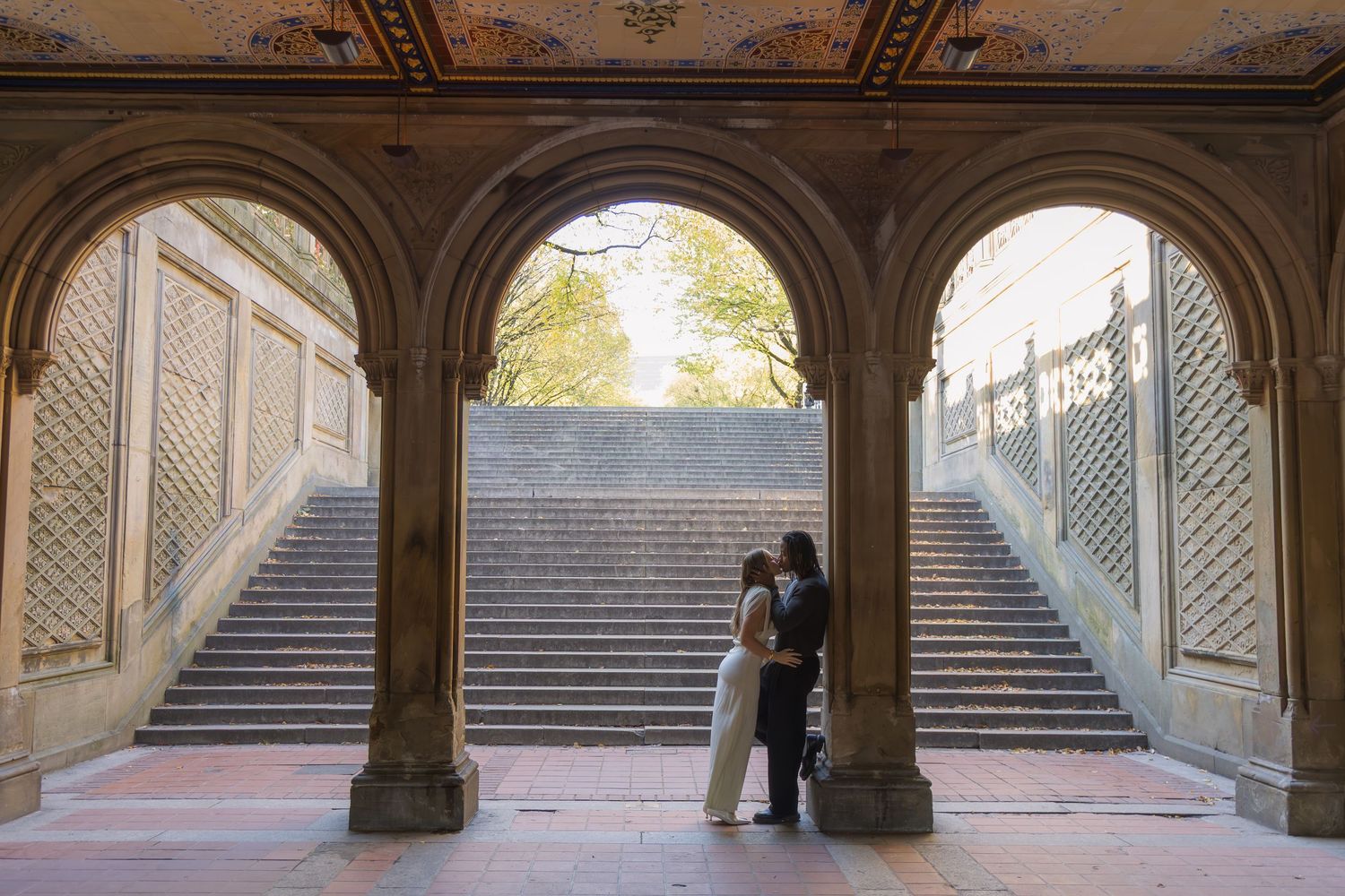 Couple leaning on one of the columns of the Bethesda Arcade archways in romantic silhouette lighting