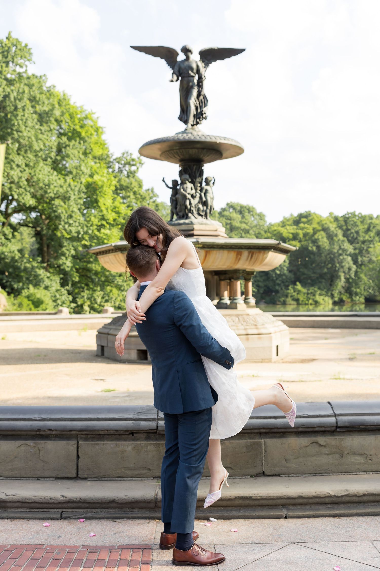 Couple embracing in front of Bethesda Fountain in Central Park, NYC, during their wedding day.