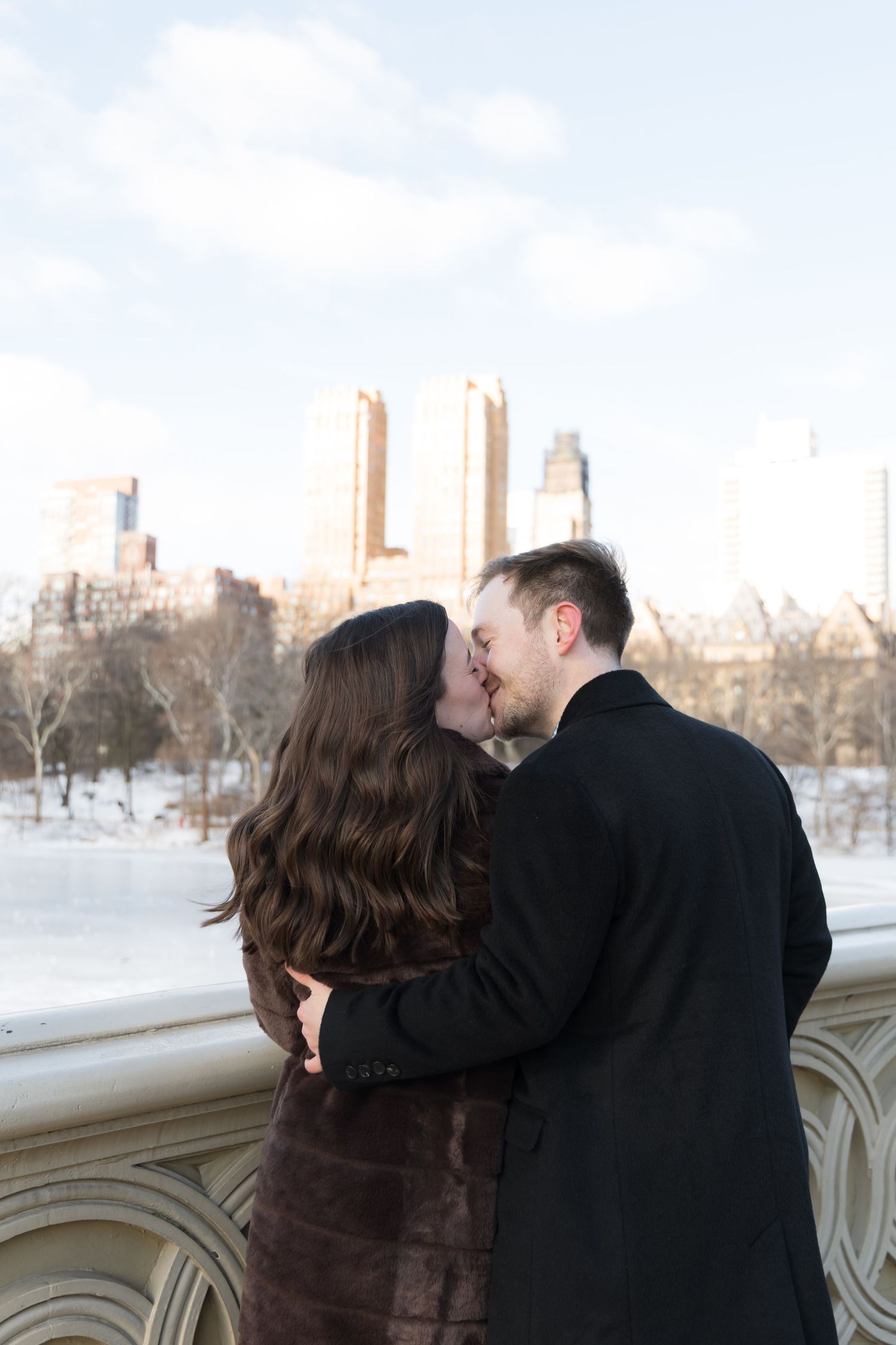 A newly- engaged couple share a kiss on Bow Bridge in Central Park