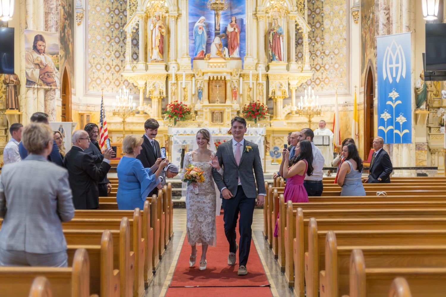 Bride and groom walk down the aisle of an ornate church after their wedding ceremony.