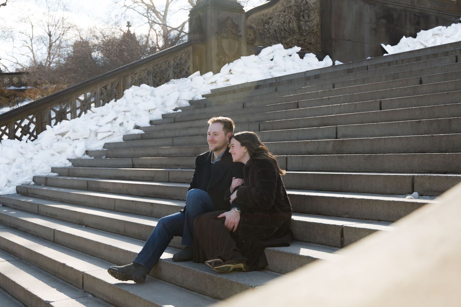 A couple sitting a the steps of the Bethesda Arcade in Central Park.