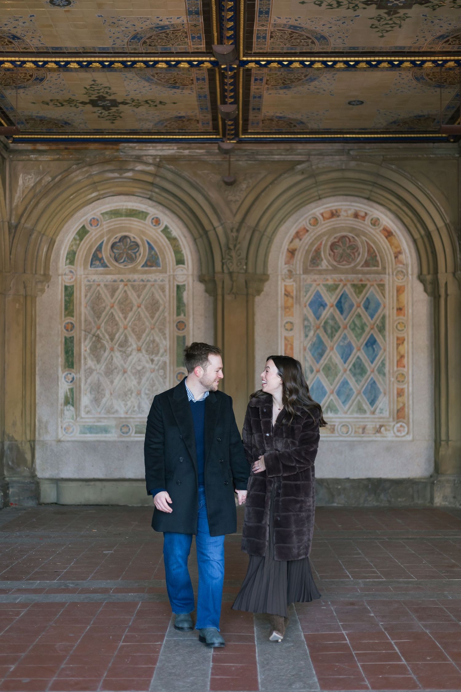 A couple walking through the arches of Bethesda Terrace.