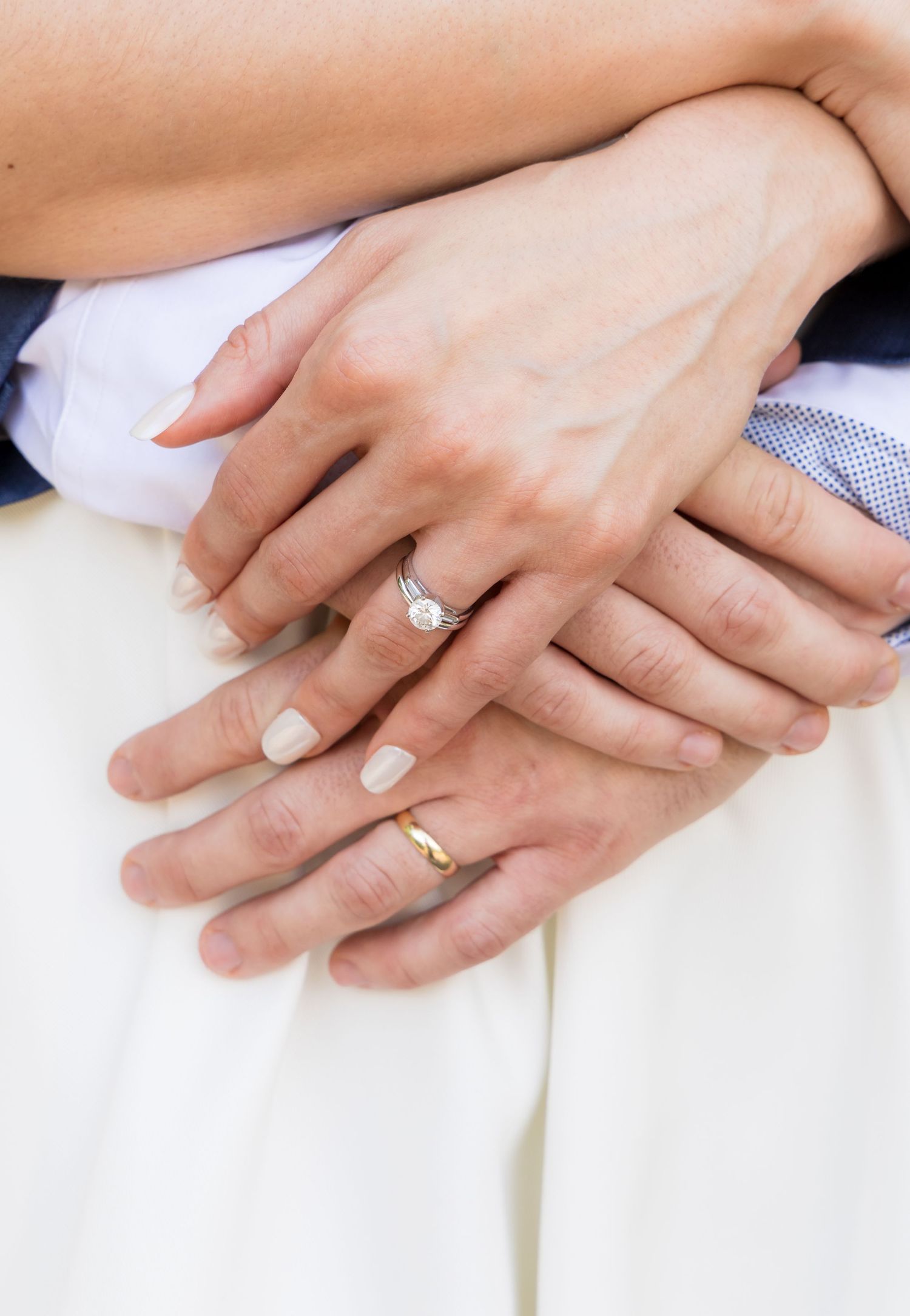 Close-up of couple's hands showing diamond engagement ring and gold wedding band after ceremony.
