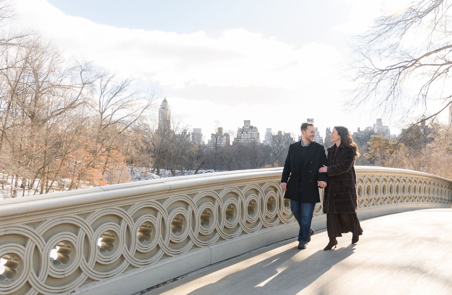 A newly- engaged couple walks on the Bow Bridge in Central Park.