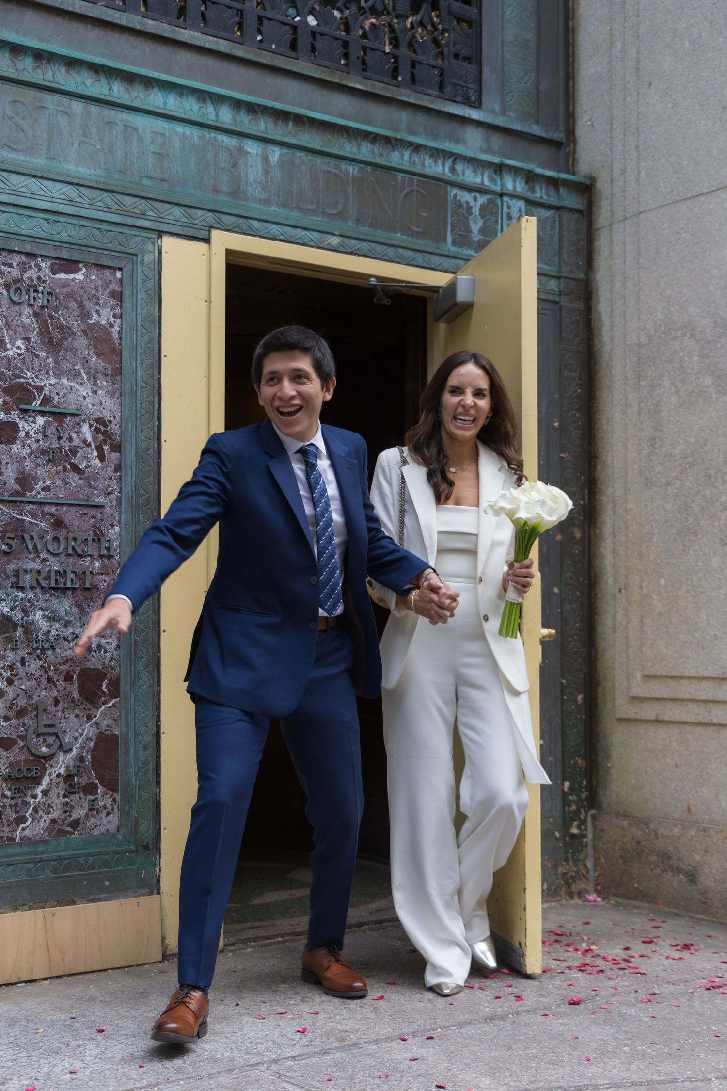 Excited newlyweds walking out of the ceremony room holding their marriage certificate