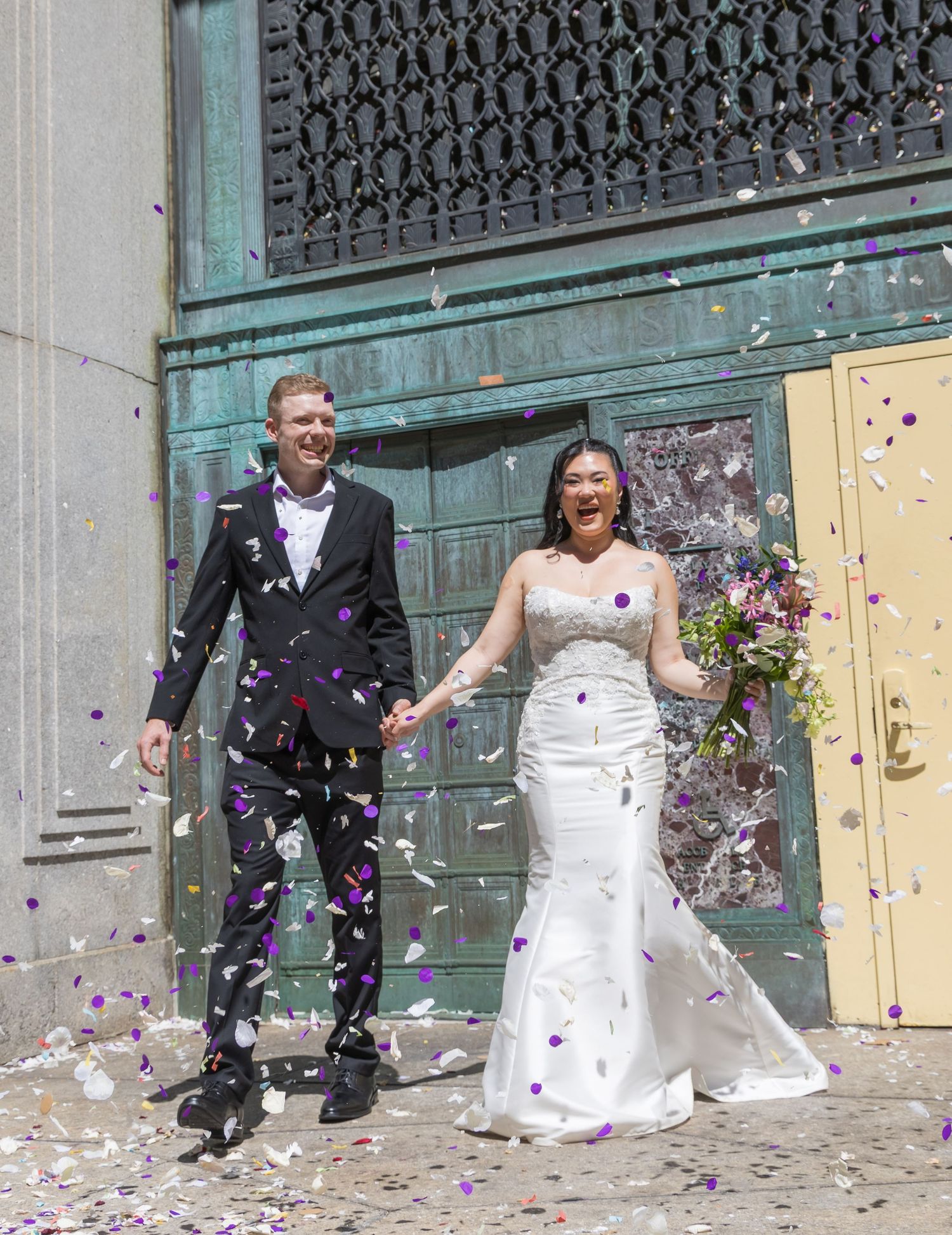 Excited newlyweds walking out of the ceremony room holding their marriage certificate with confetti being thrown
