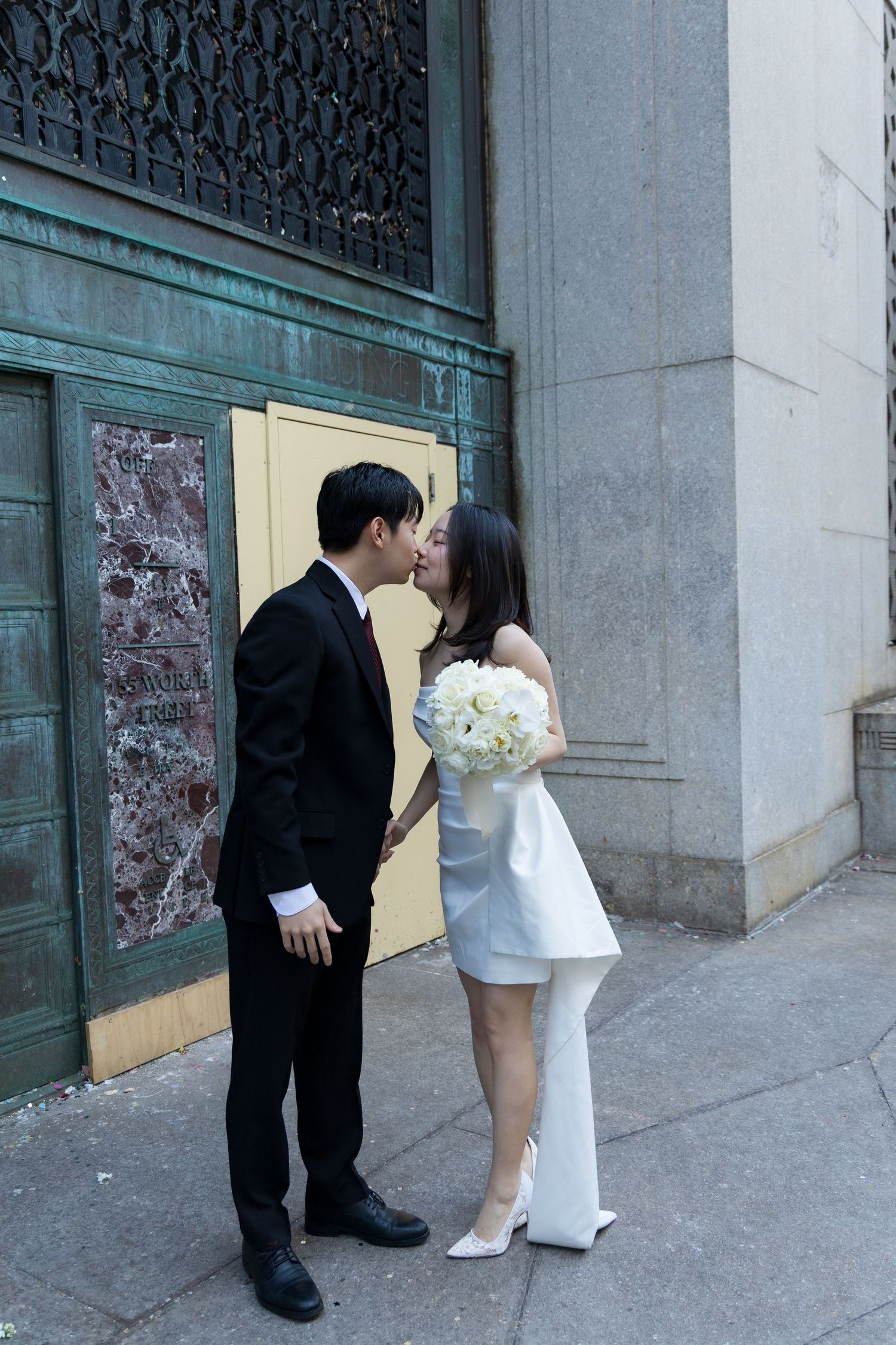Newlyweds sharing their first kiss outside the marriage bureau as they exit