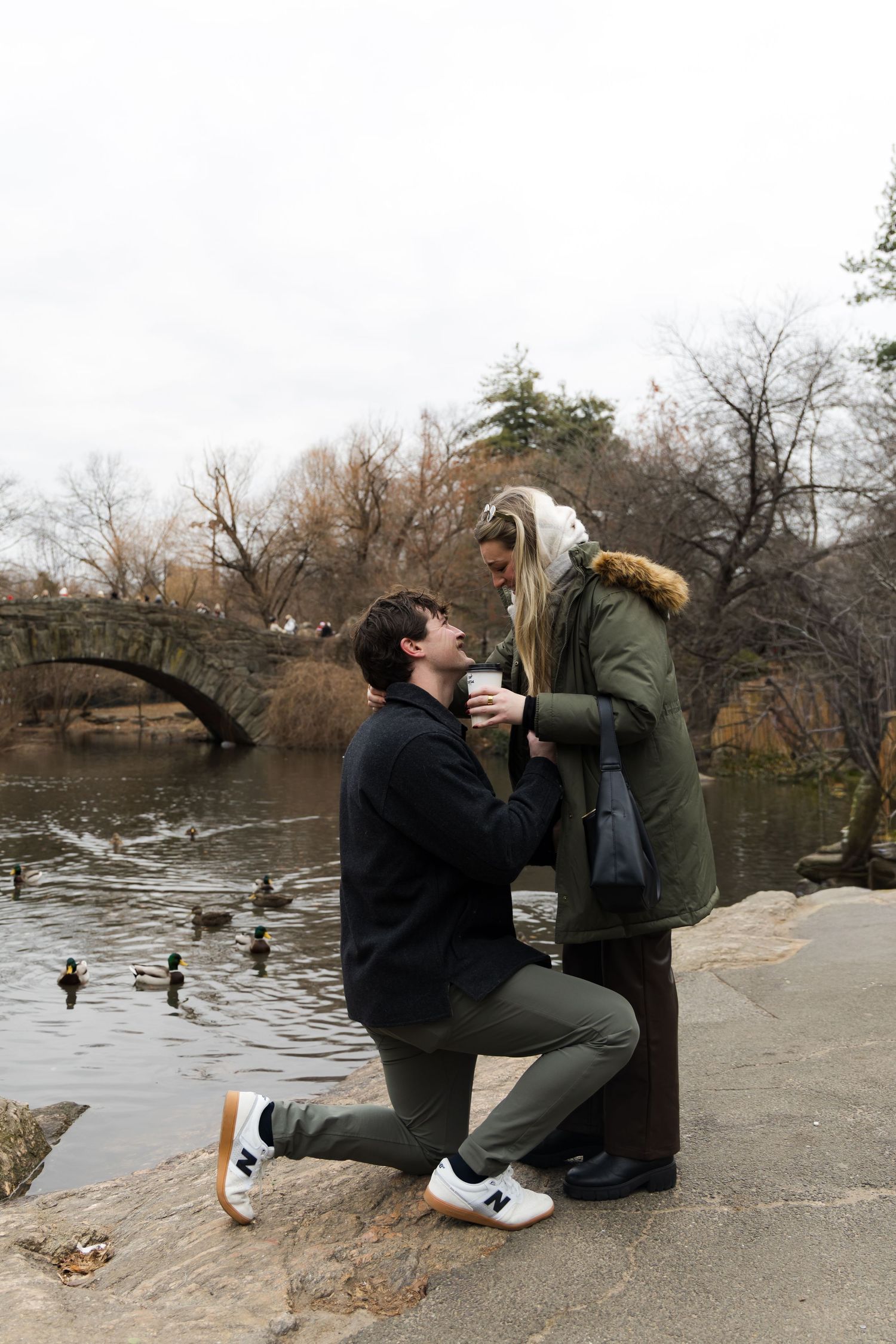 Proposal moment with the Gapstow Bridge in the background in the wintertime