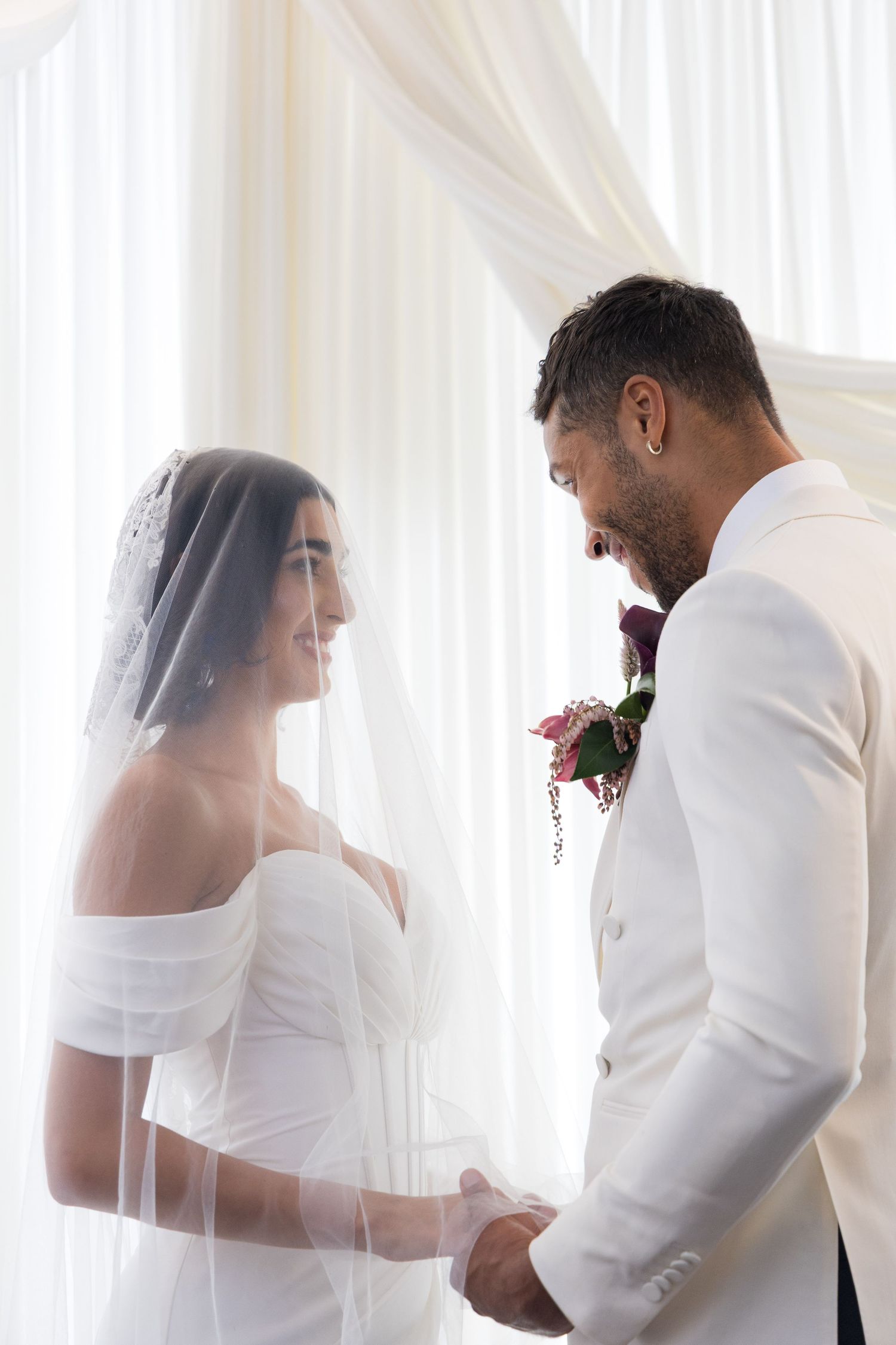 A romantic series of wedding photos showing a couple in white sharing tender moments behind sheer curtains.