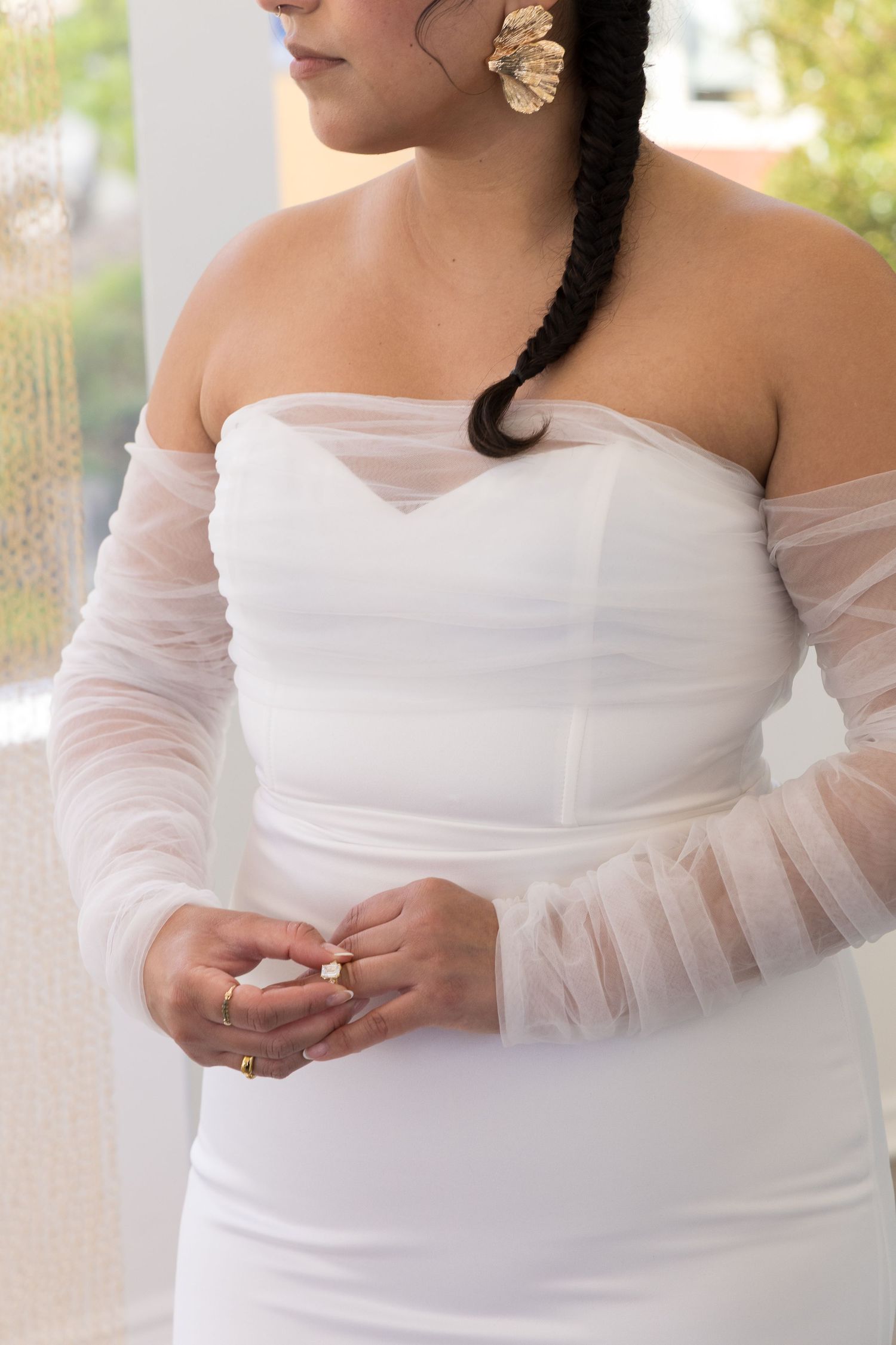 Bride in her white dress fiddling with her ring looking away.
