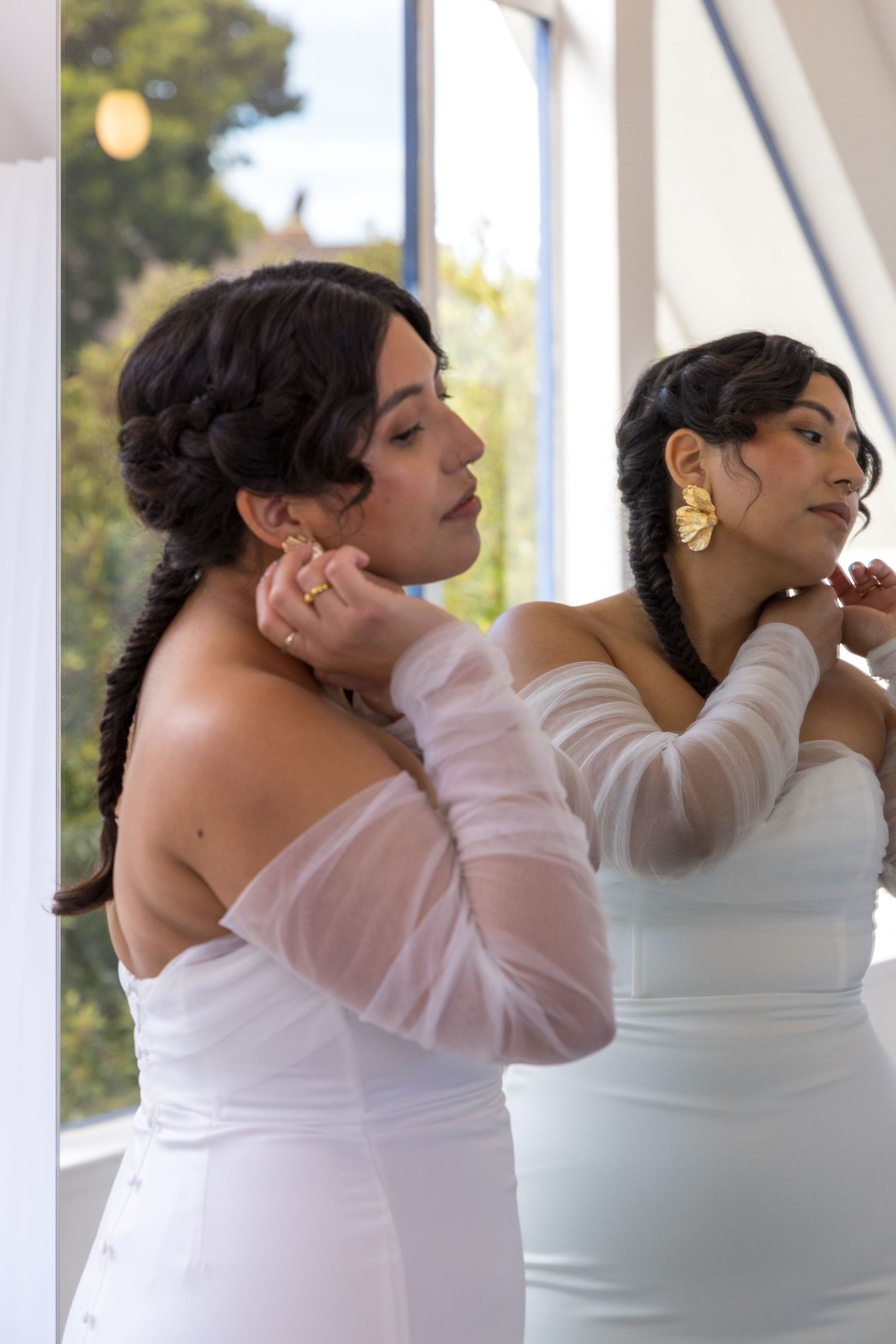 Bride putting her earring on in front of a mirror