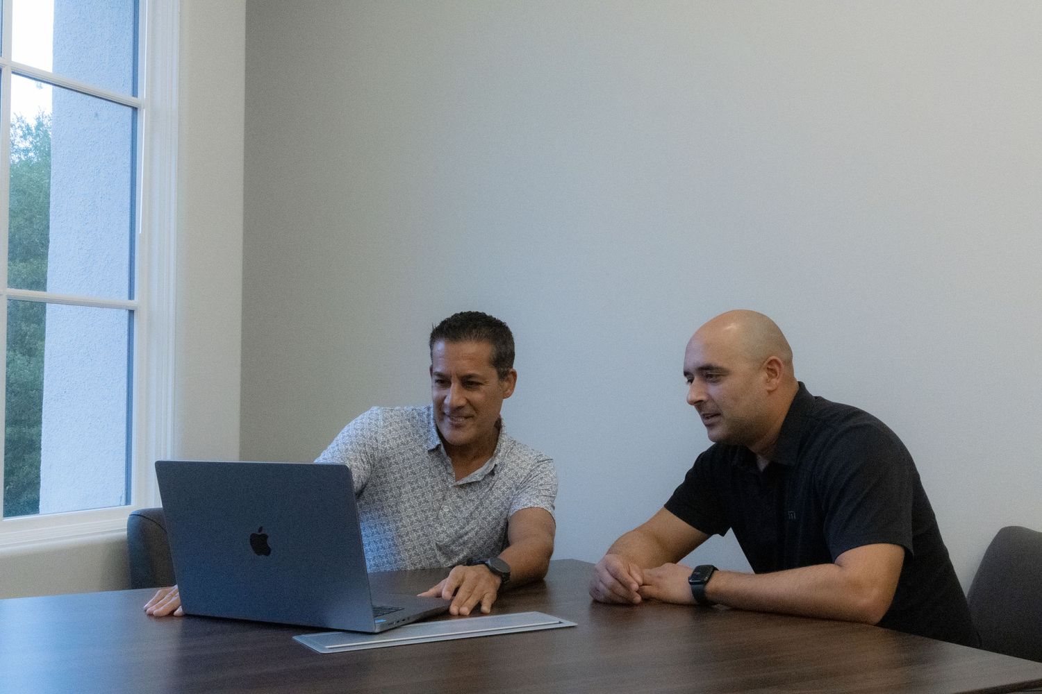 Group of people working at laptops in a bright modern office meeting room.