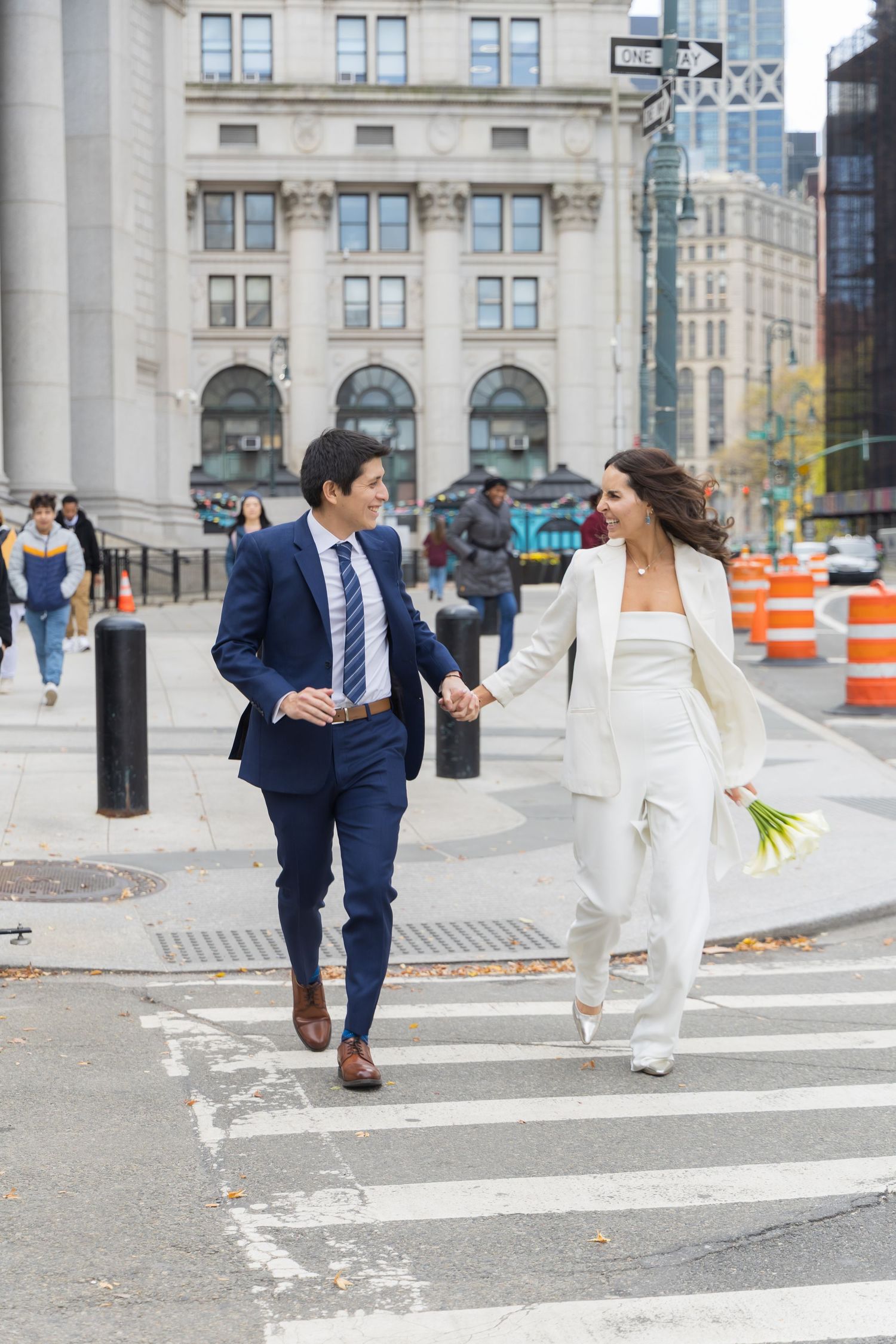 Couple hand in hand walking across the street of the NYC Marriage Bureau.