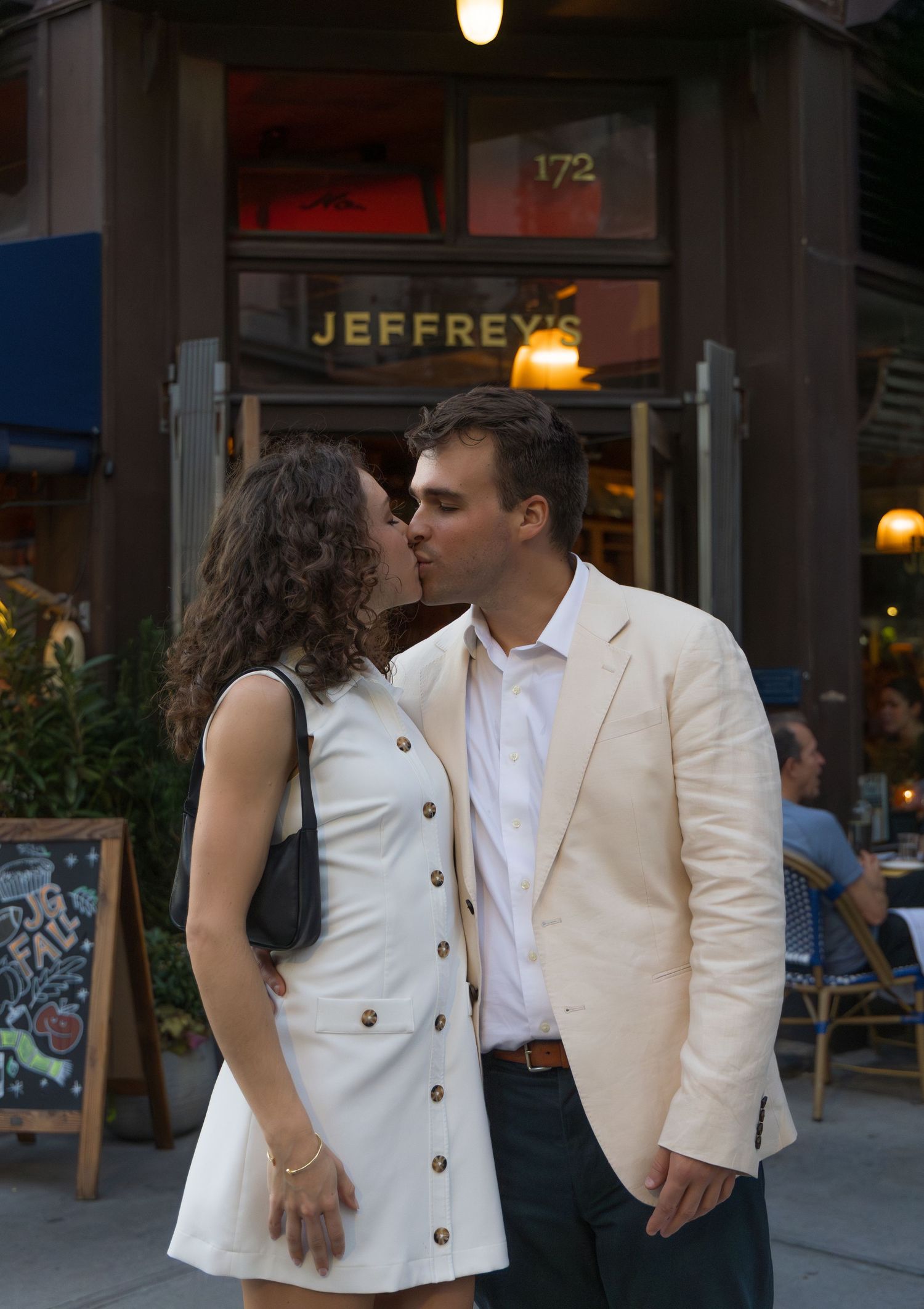 couple kissing in front of NYC restaurant Jeffery's Grocery for a west village engagement photoshoot