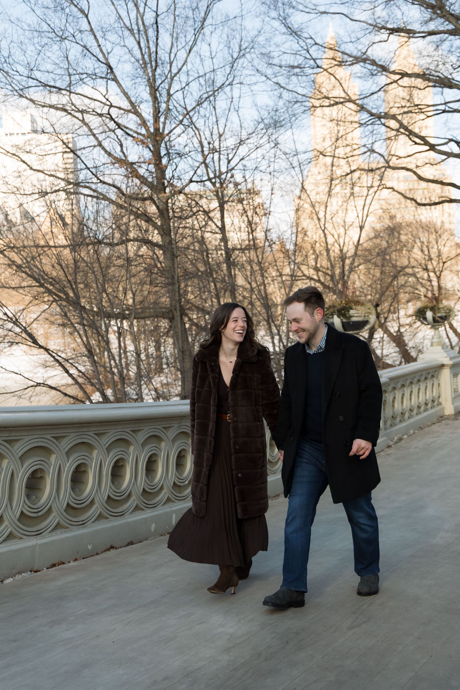 A newly- engaged couple walks on the Bow Bridge in Central Park.