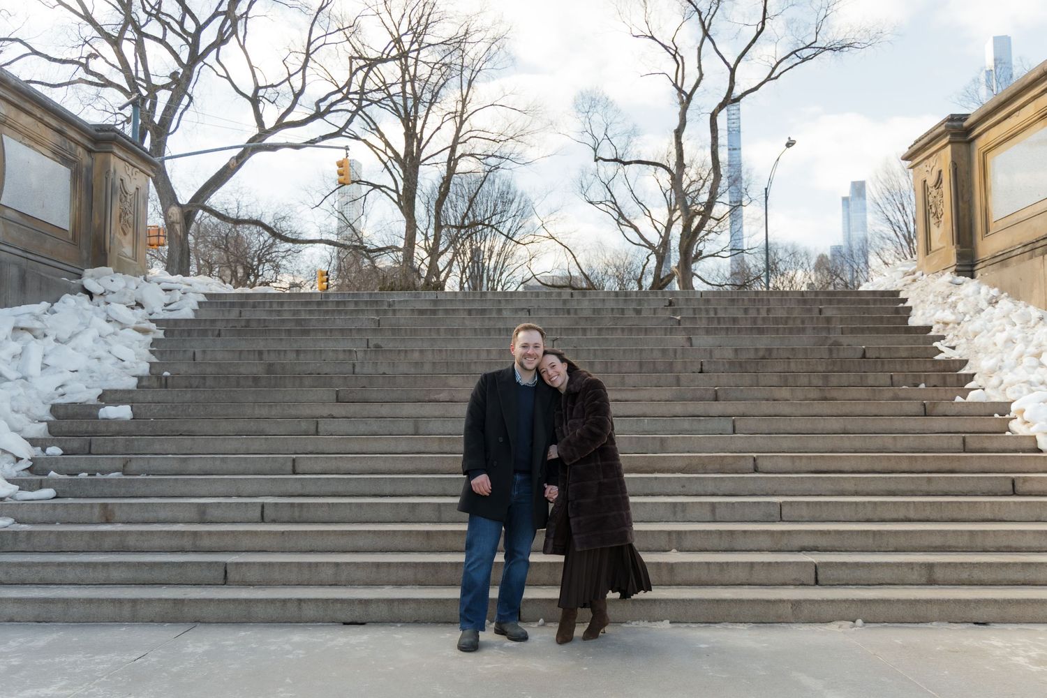 A couple standing in the middle of the steps of the Bethesda Arcade in Central Park.