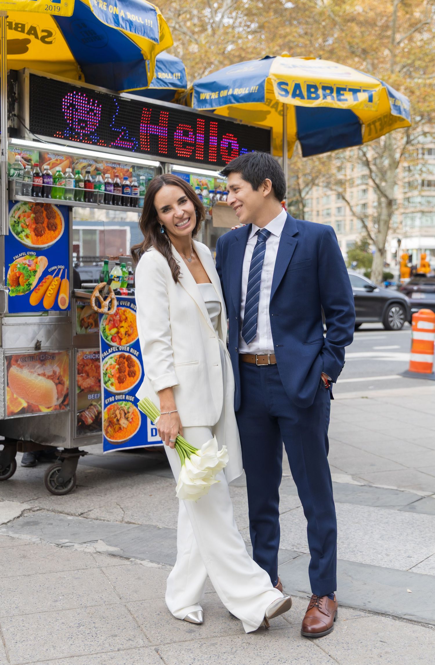 Newlywed couple posing in front of a hotdog stand in front the NYC Supreme Court building