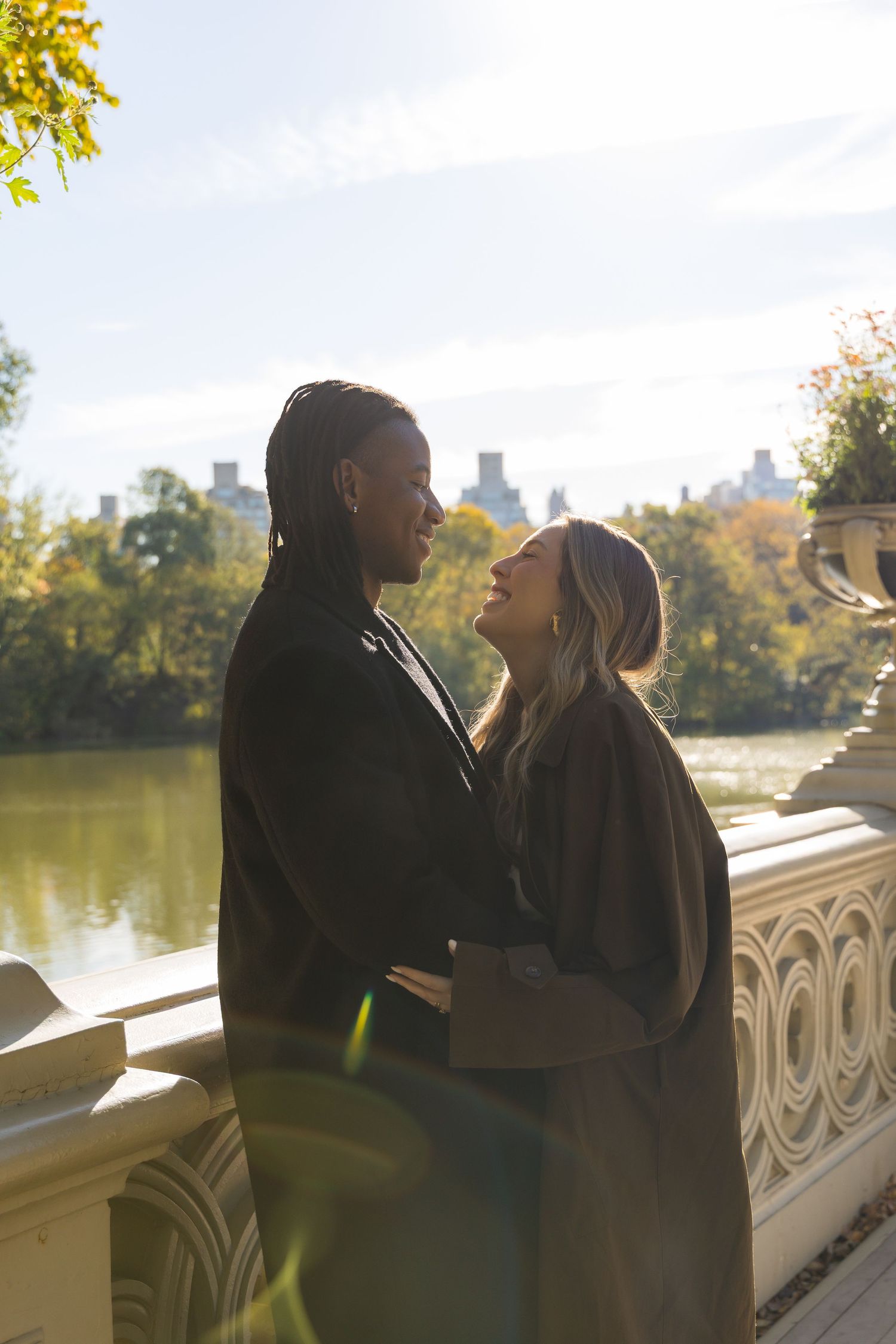 Couple laughing at each other on the Bow Bridge during golden hour