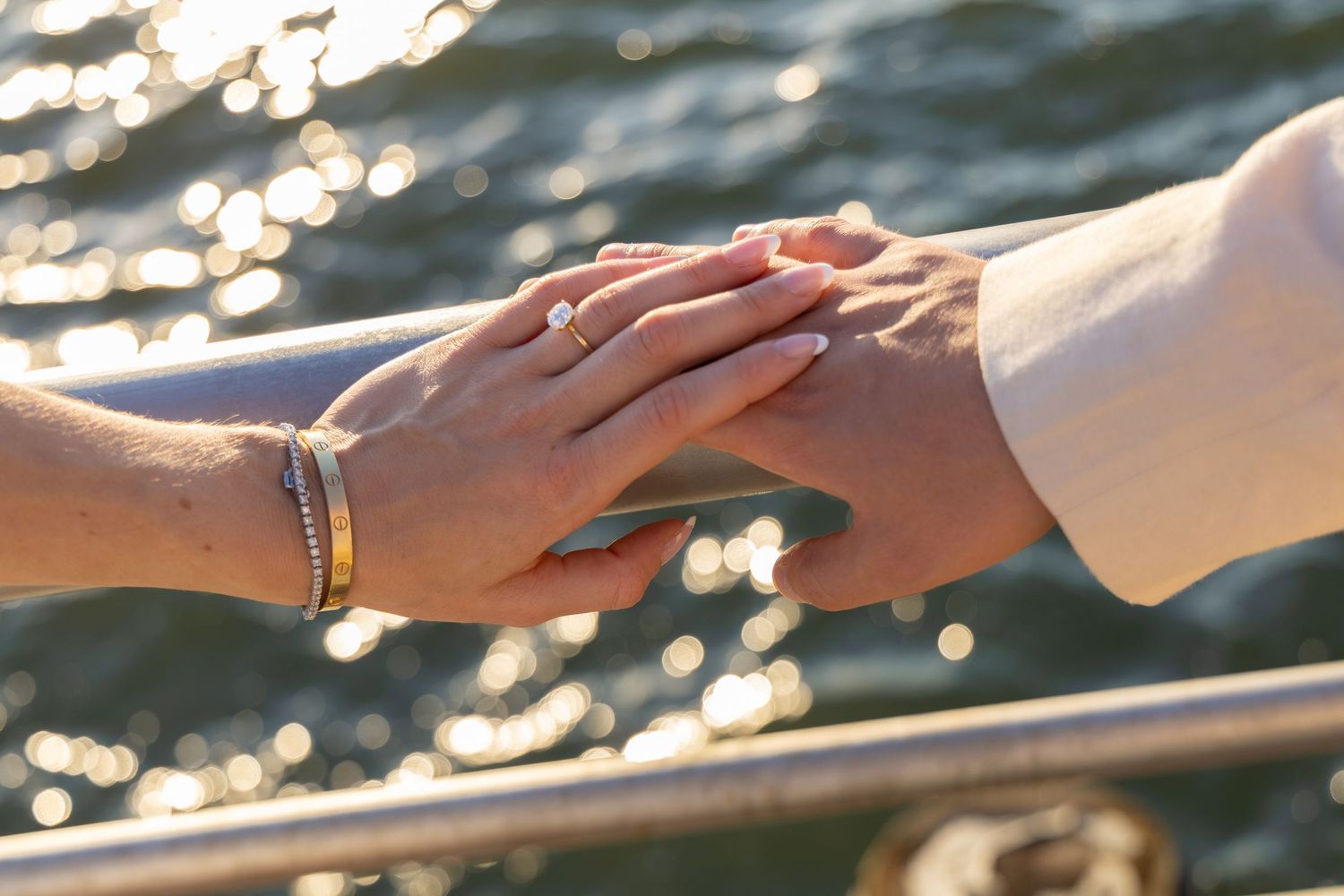 Two hands reach towards each other across sparkling water in a tender moment of connection.