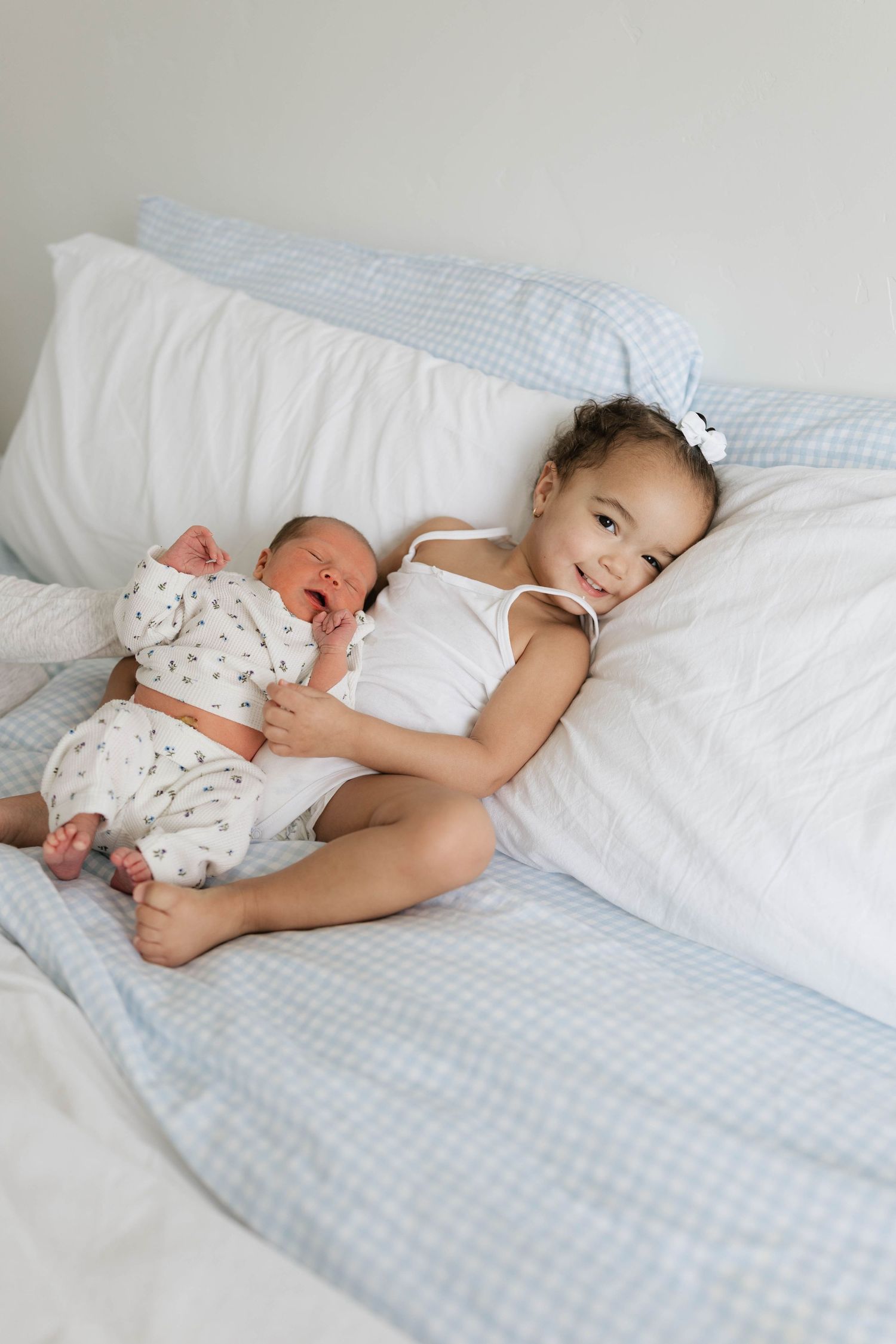 Two young children sleeping peacefully together in white bedding with soft blue accents.