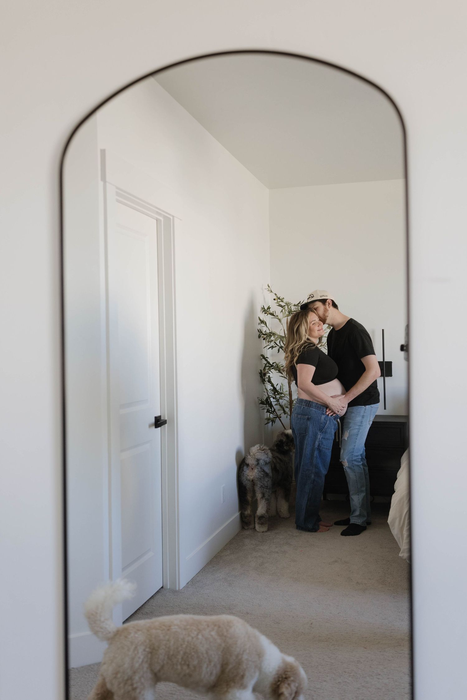 A couple embraces in a hallway while dogs rest nearby.