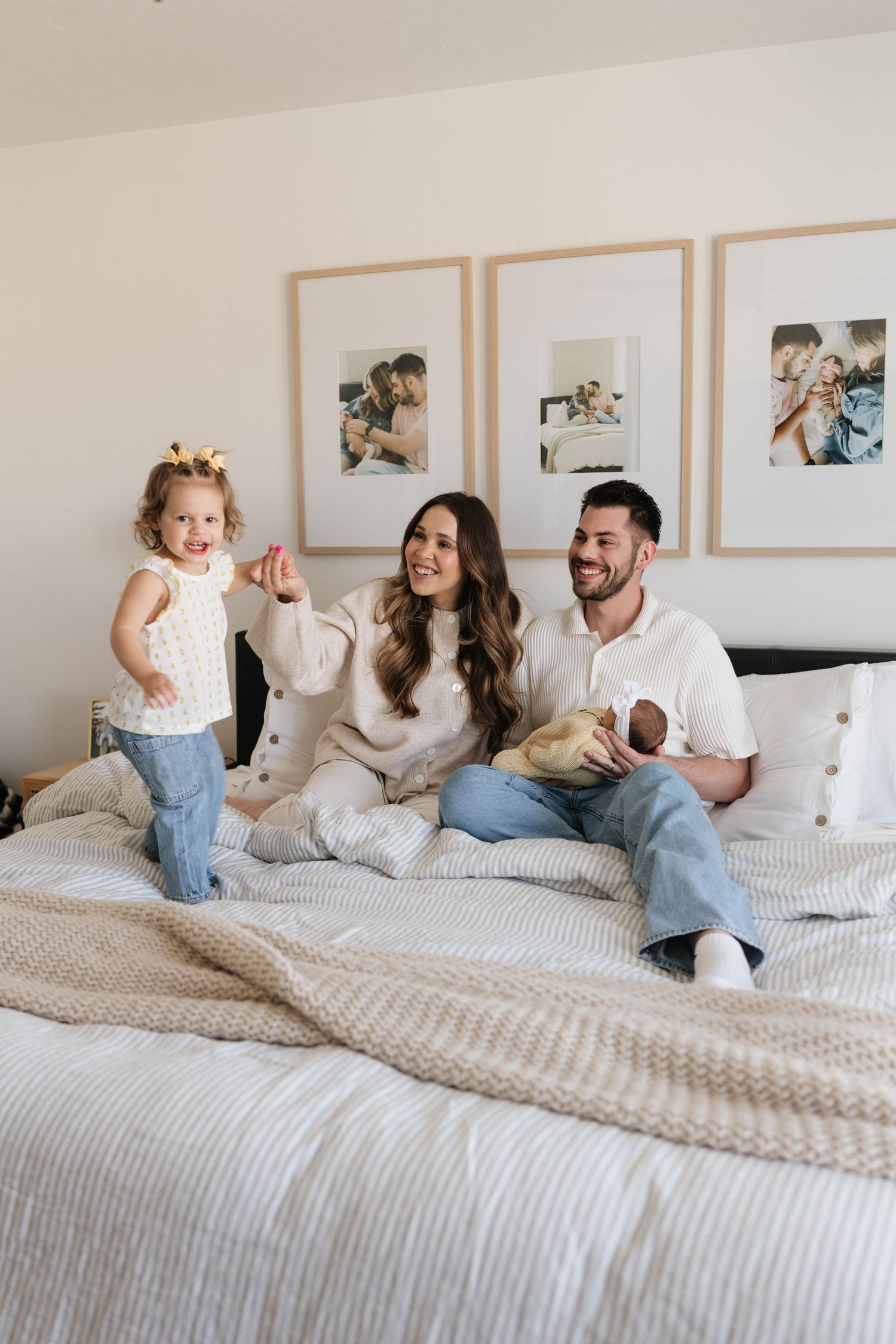 A family and their dog share joyful moments while relaxing together on a cozy bed with white linens.