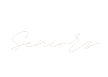 Elegant cursive neon sign spelling Seniors in white light against a clean white background.
