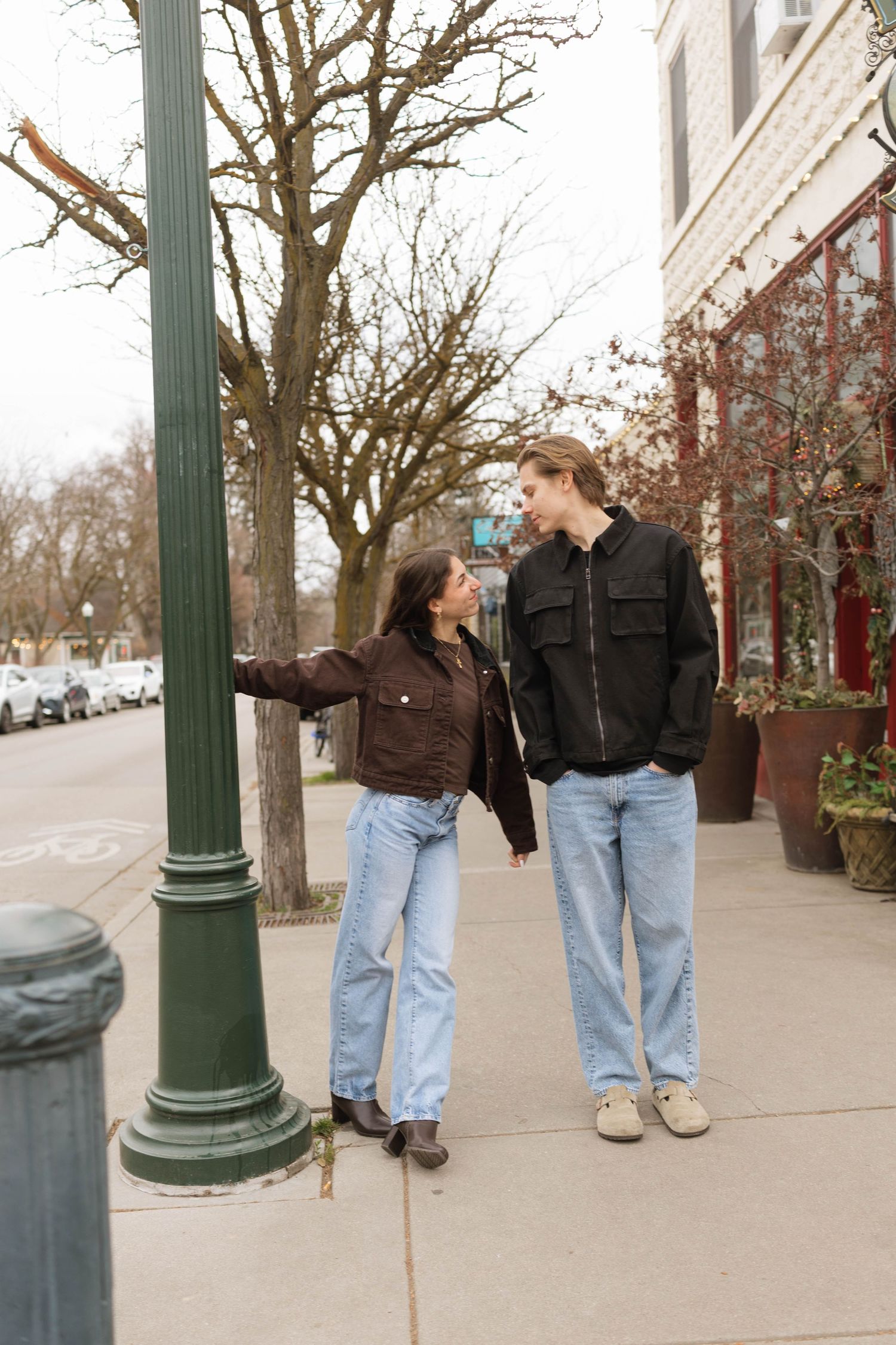 A sequence of five photos showing two people walking and interacting with a green lamppost on a city sidewalk.