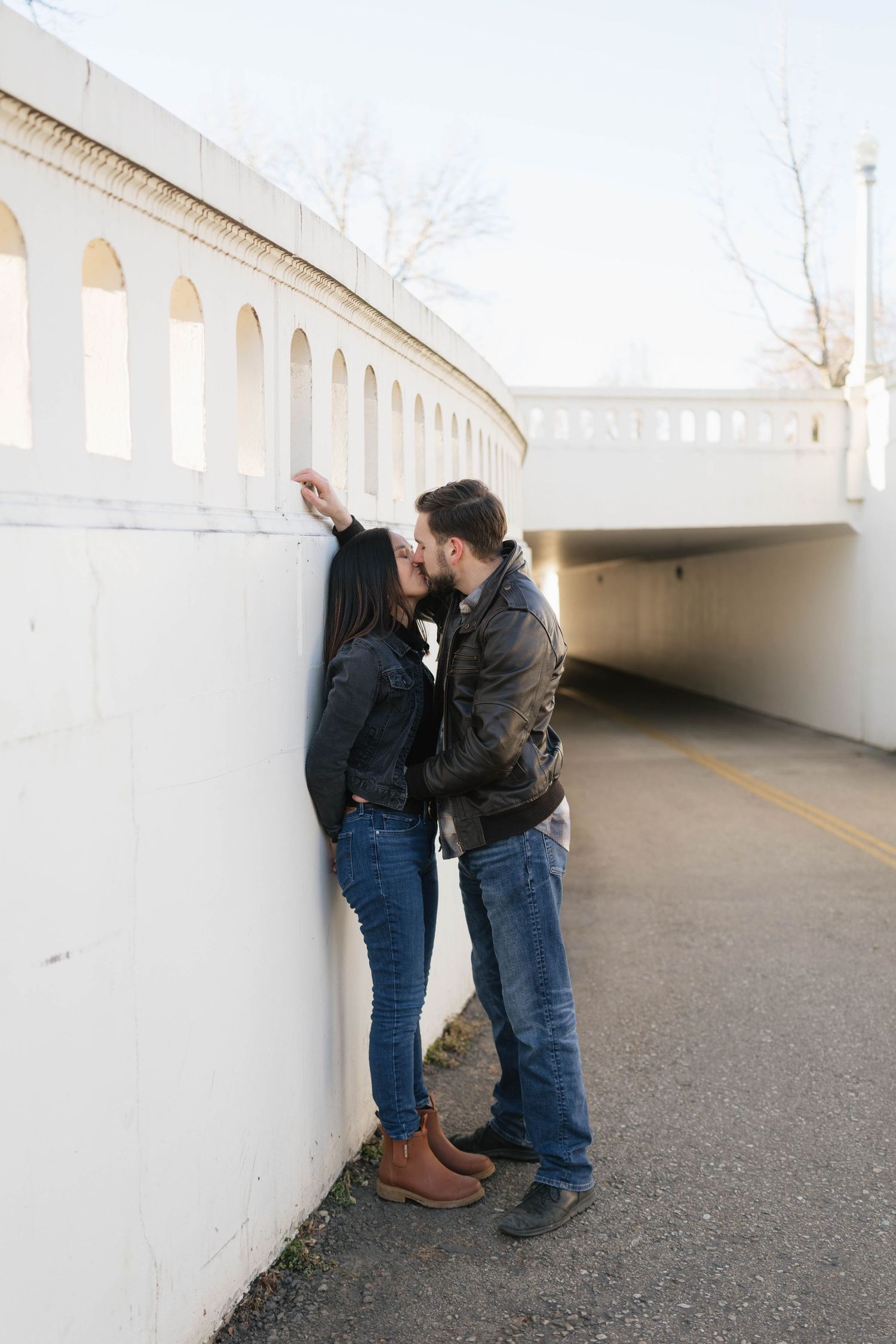 A couple shares an intimate moment while standing in a white tunnel walkway.