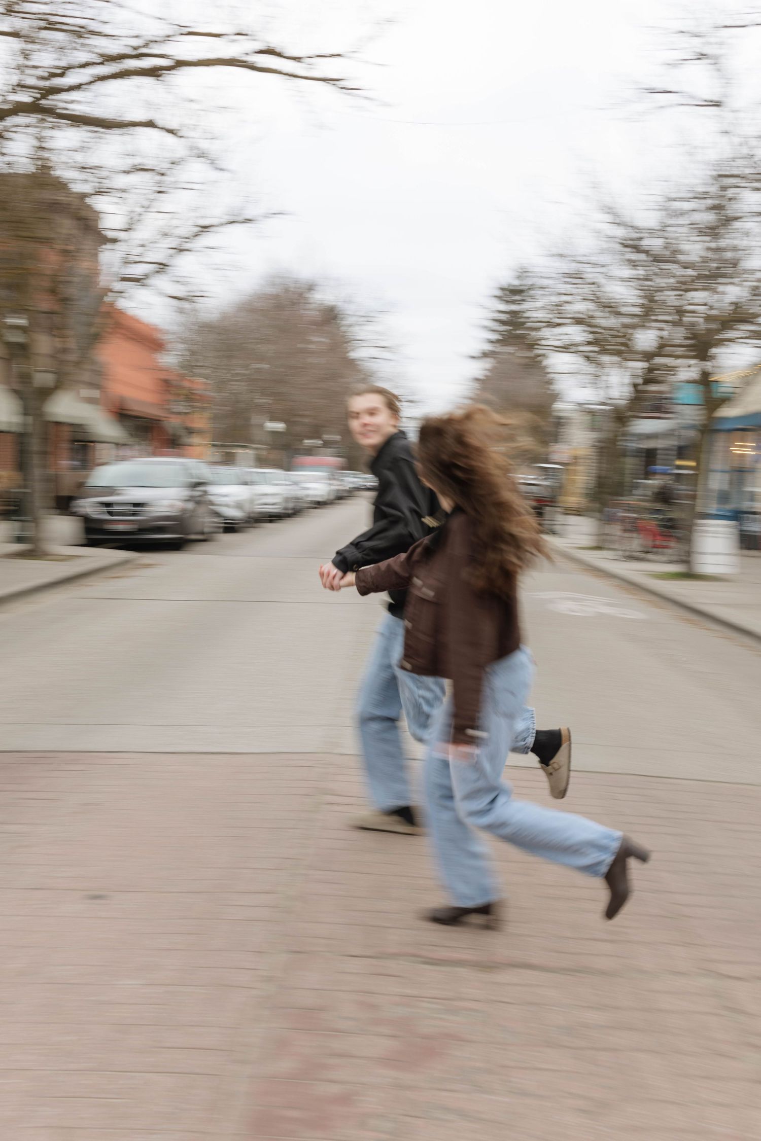 A sequence of motion shots showing someone with long hair running and twirling on a city sidewalk in jeans.