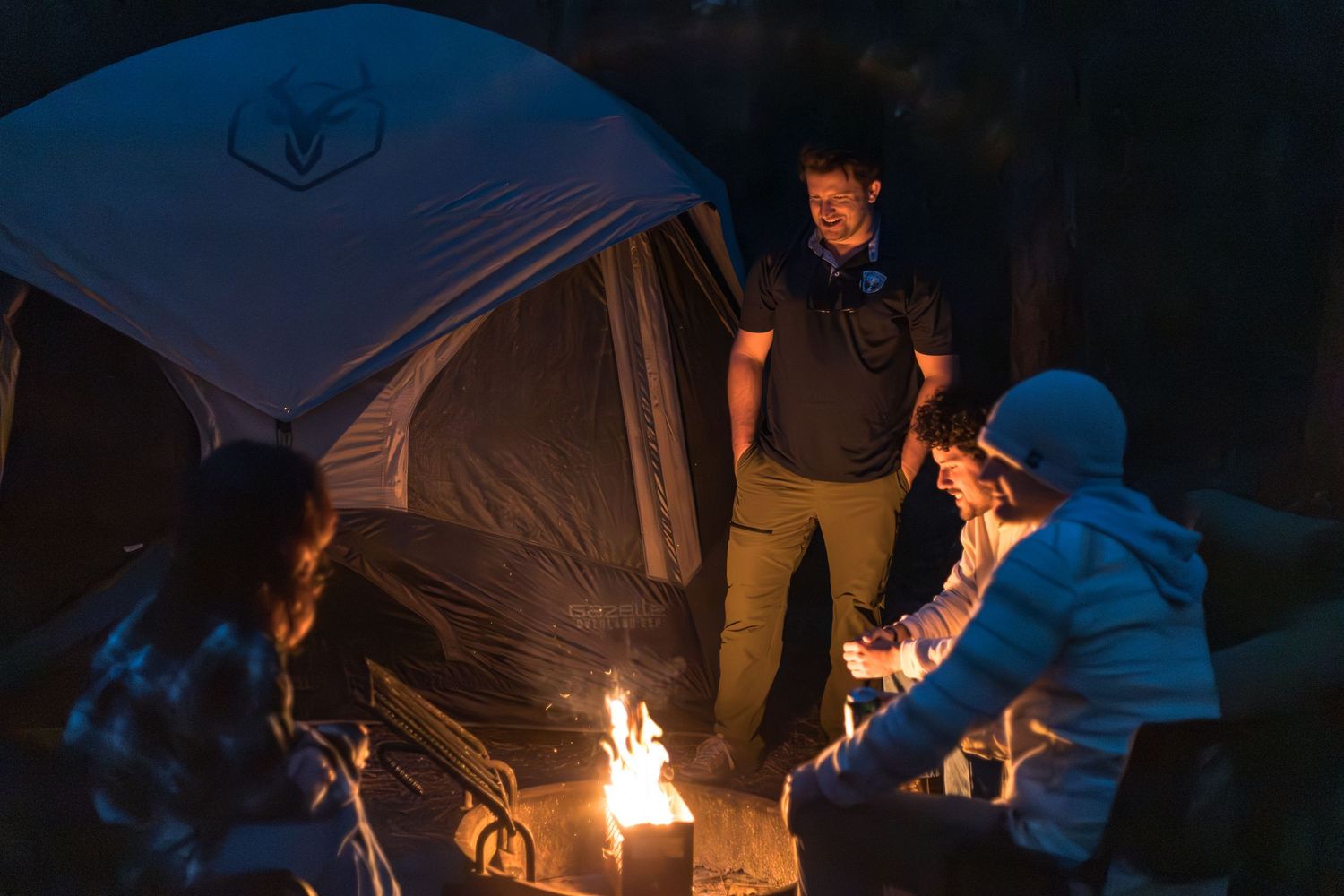 Group of people gathered around a campfire at night creating a warm glowing atmosphere.