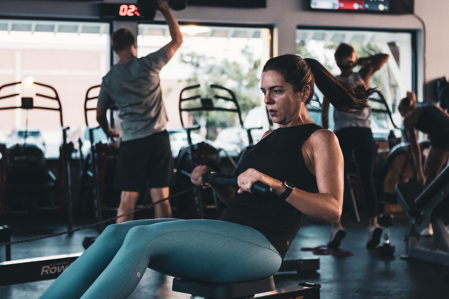 People exercising in a dimly lit fitness studio with equipment.