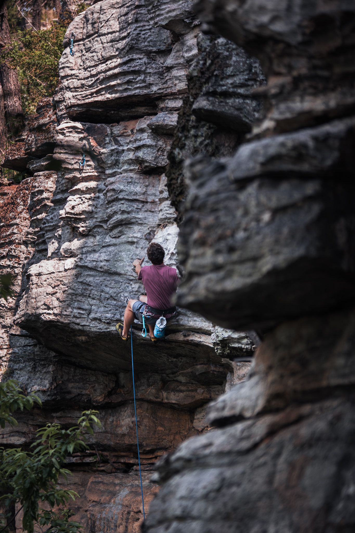 Rock climber scaling a challenging limestone cliff face at Pilot Mountain, NC during an outdoor climbing session.