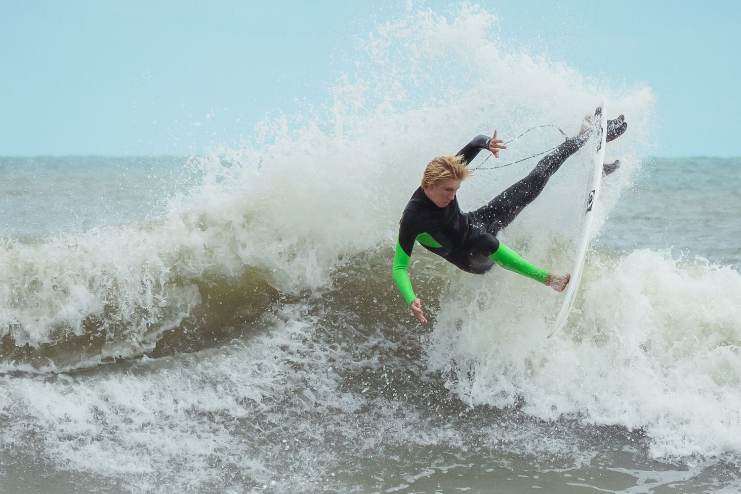 Dynamic surfing action shot showing impressive wave spray during a tail release turn in Wrightsville Beach, NC