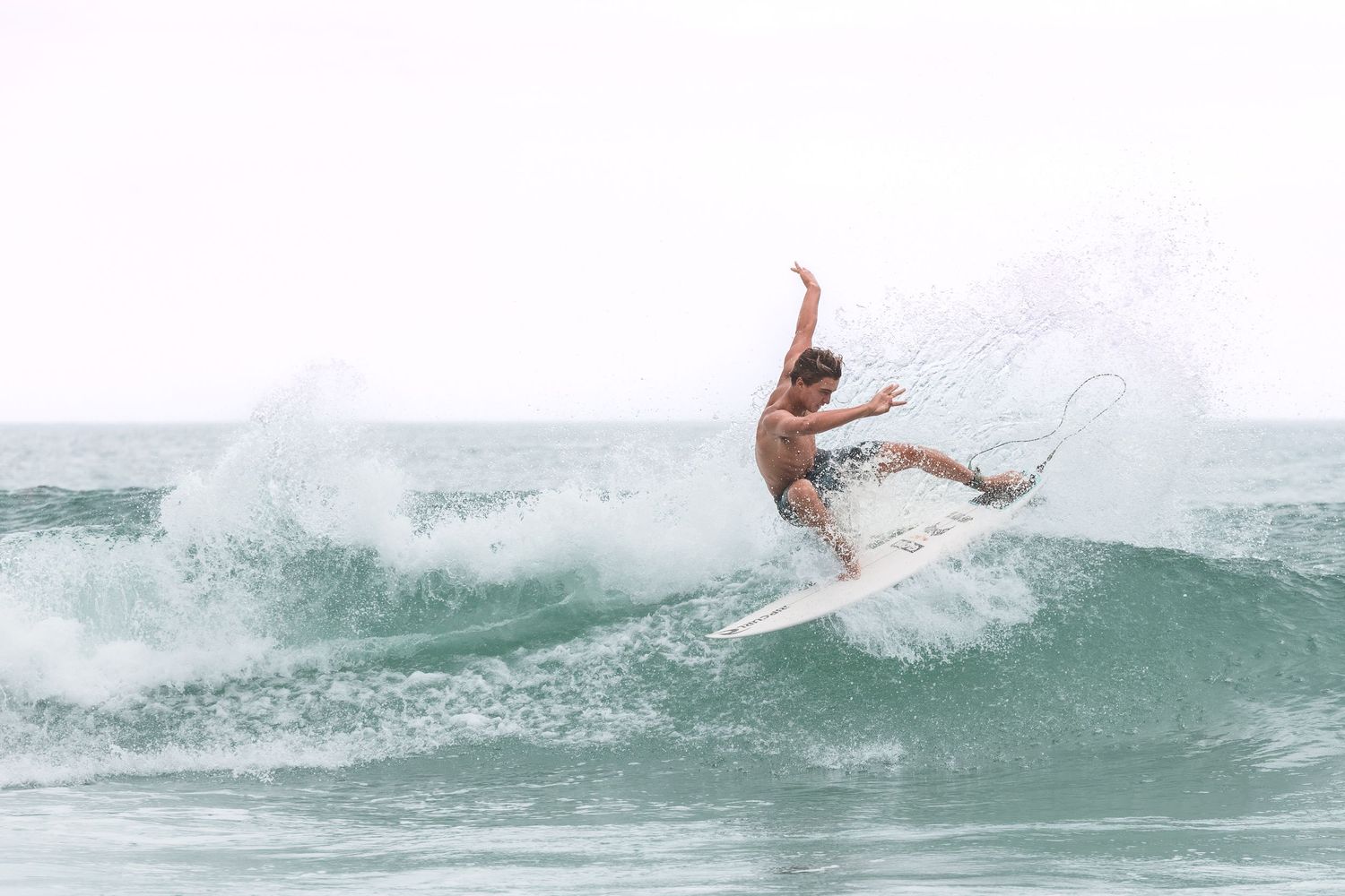 Surfer performing a maneuver on a breaking ocean wave in Wrightsville Beach, NC