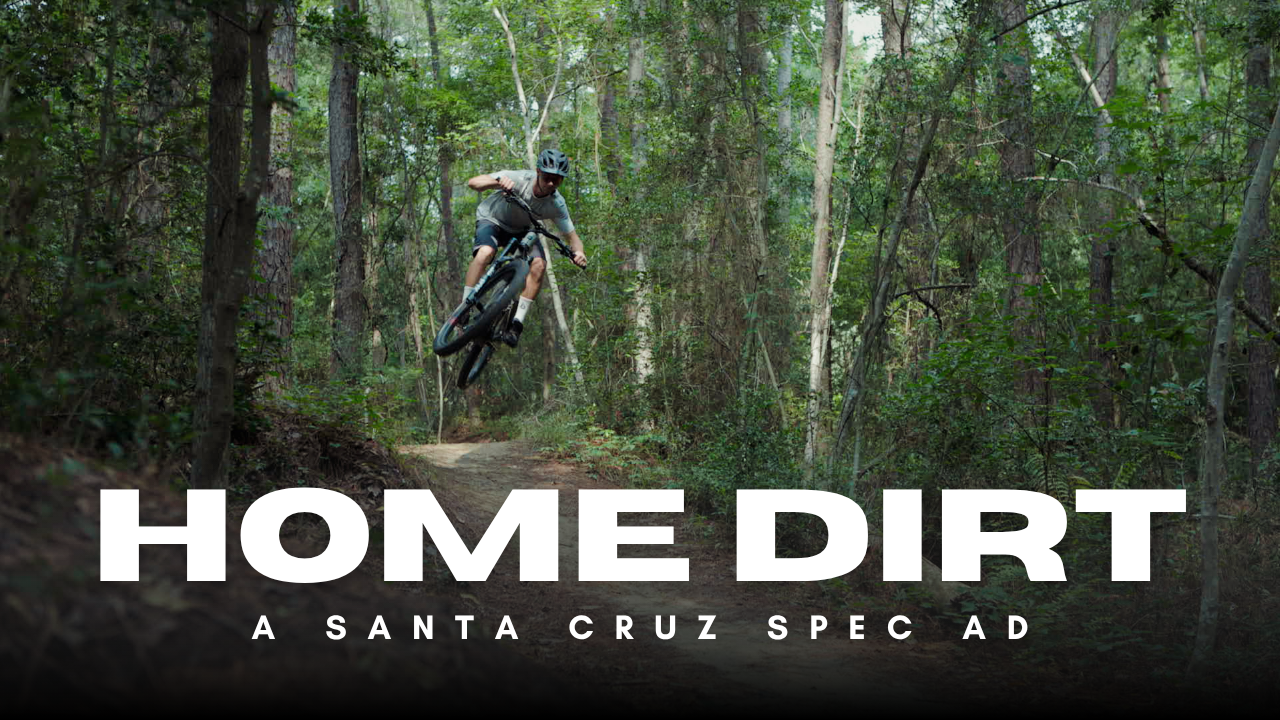 Mountain biker performing aerial trick on forest trail in Santa Cruz spec ad titled Home Dirt.