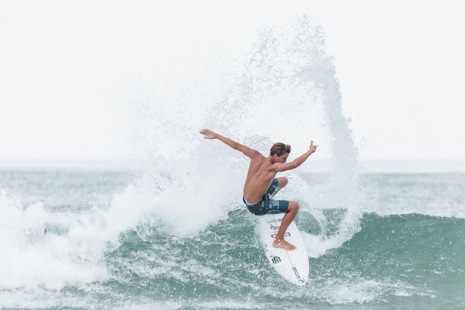 Action shot of surfer riding turquoise wave with dramatic white spray in Wrightsville Beach, NC