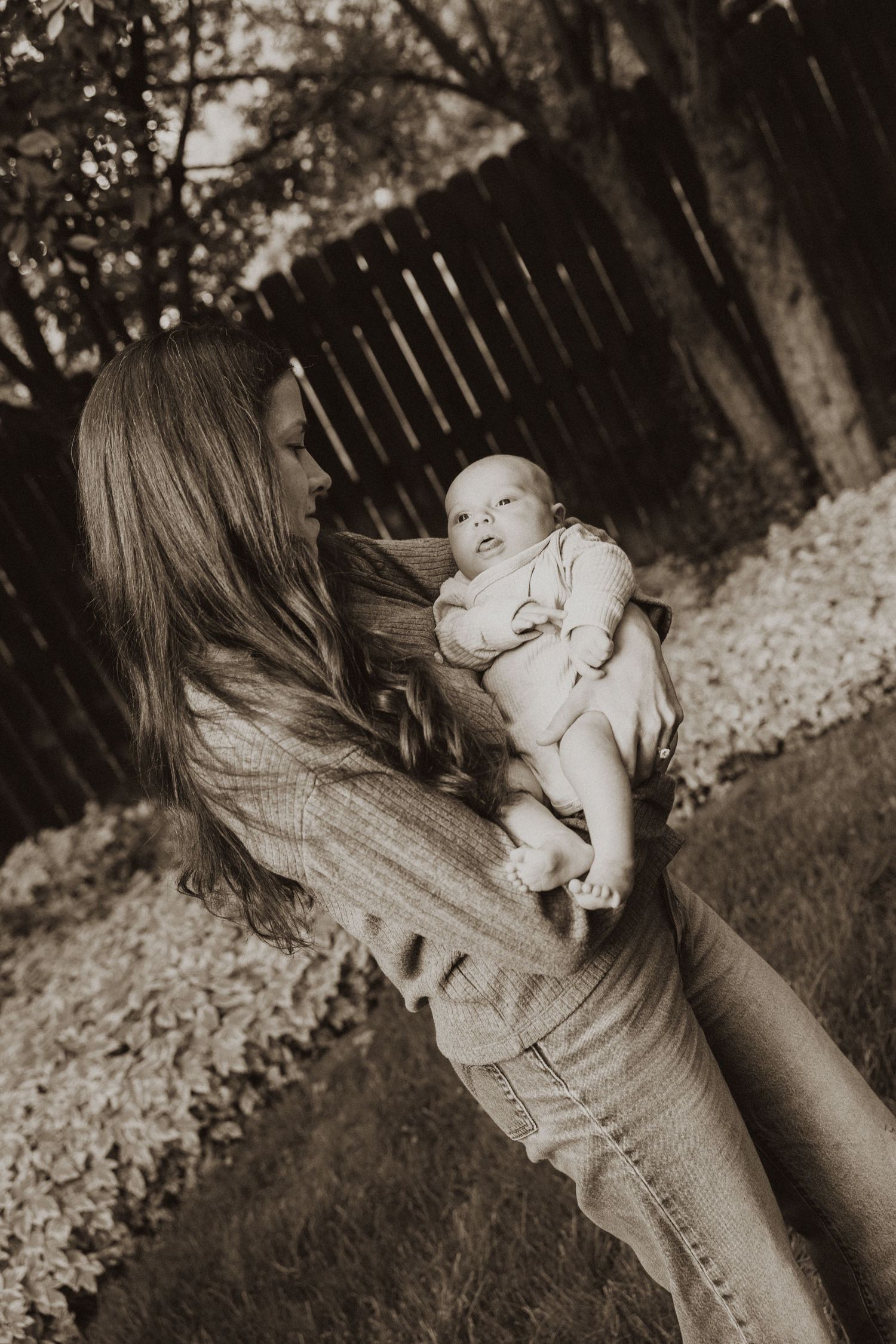 Mother tenderly holding her newborn baby outdoors in a vintage sepia-toned photograph.