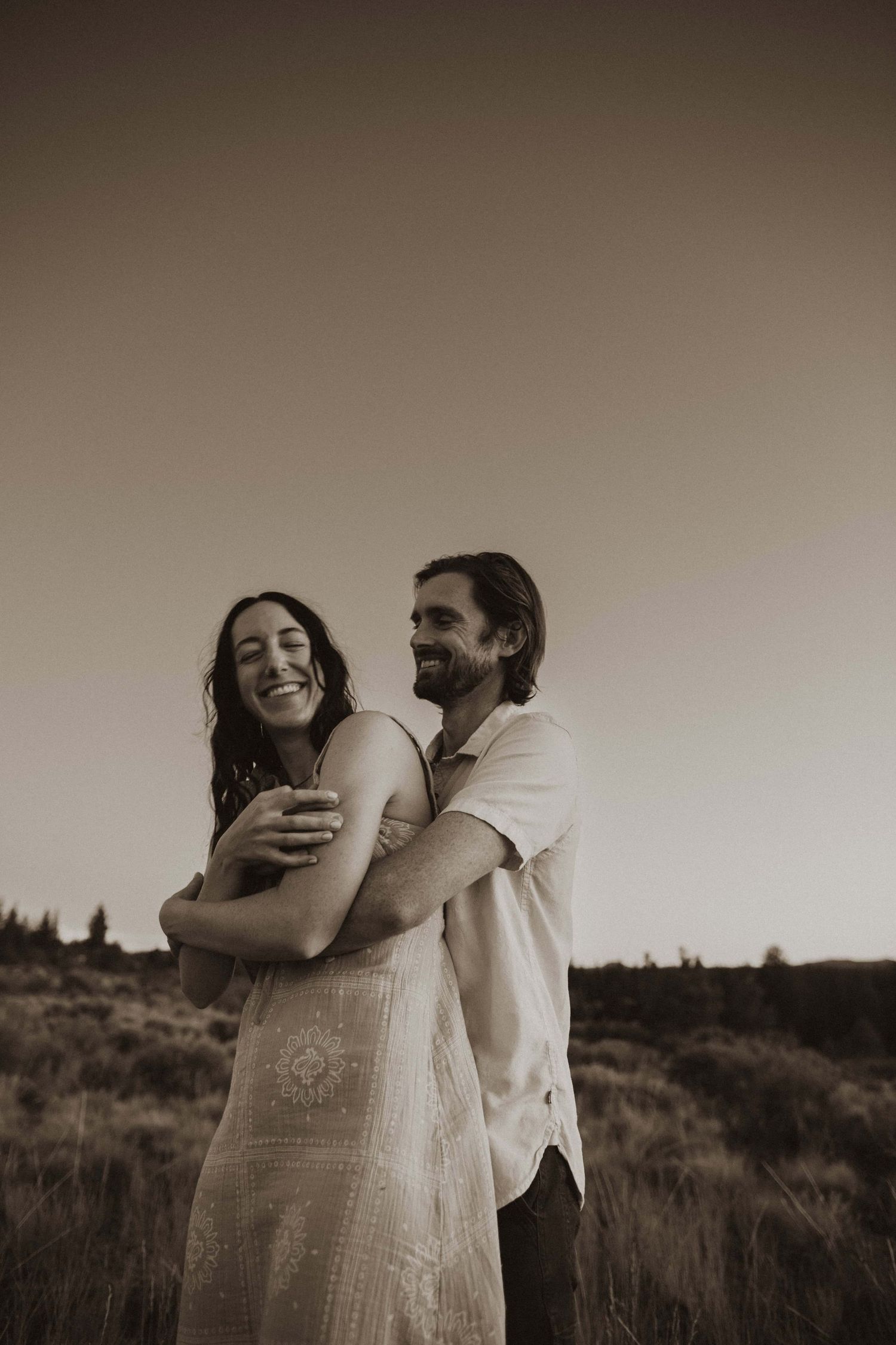 A couple laughs and embraces in a desert setting with dramatic lighting.