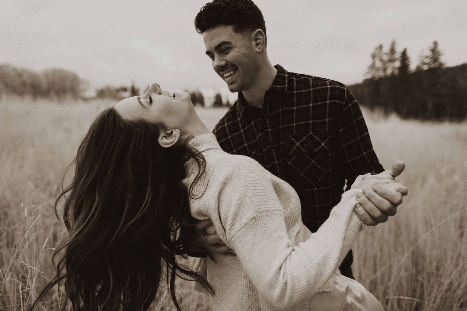 Black and white portrait of couple embracing in rural field setting.