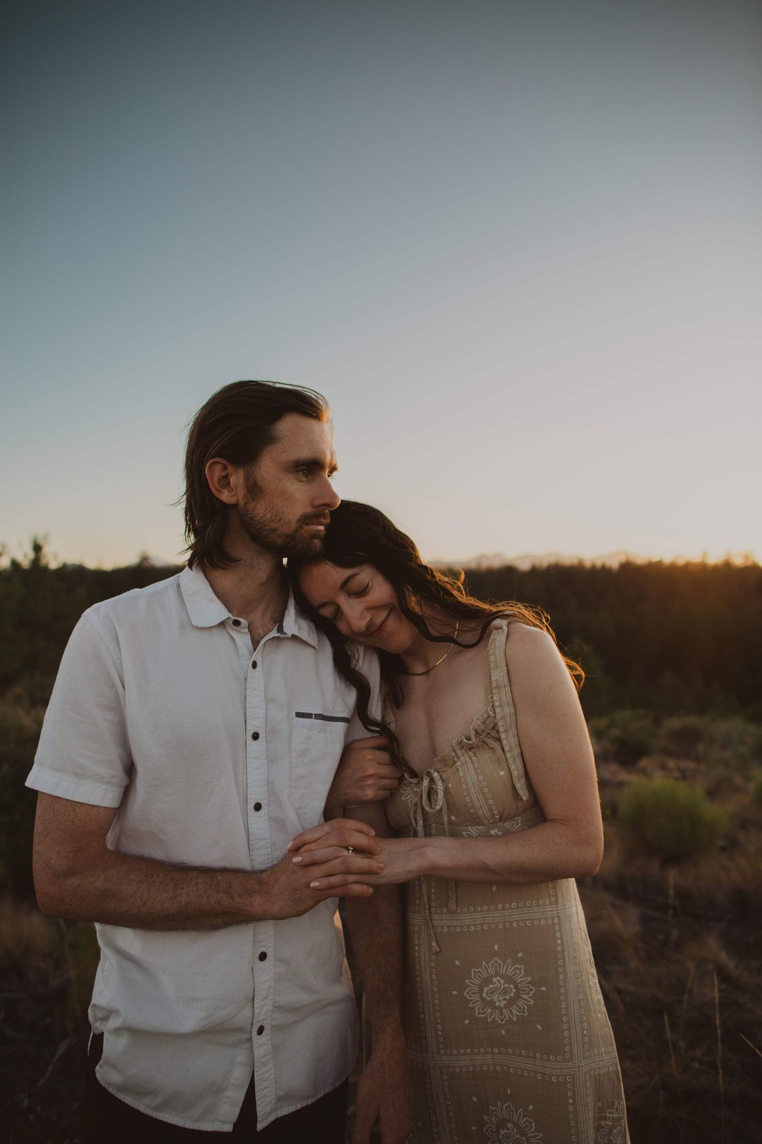 Two people share intimate moments in desert scenery during sunset.
