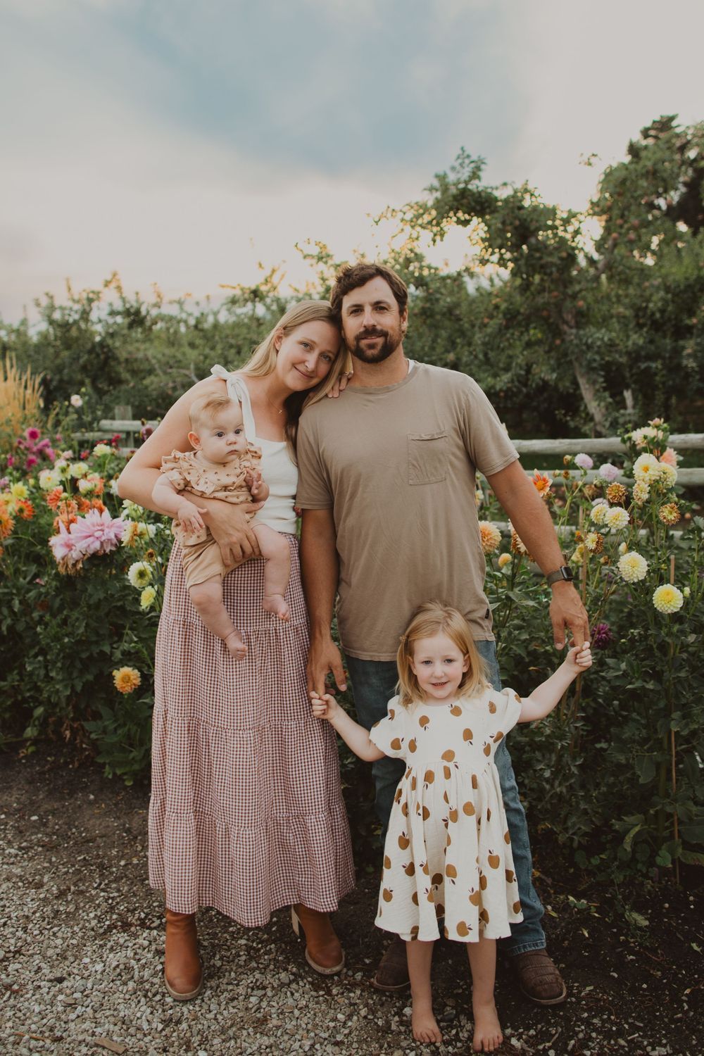 Family portrait in a blooming rose garden with warm evening light and coordinated casual outfits.