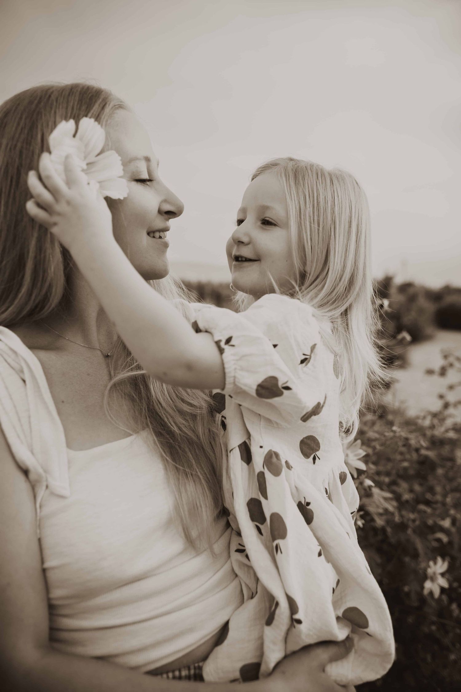 Candid black and white portraits showing joyful laughter and connection between two people in a garden setting.