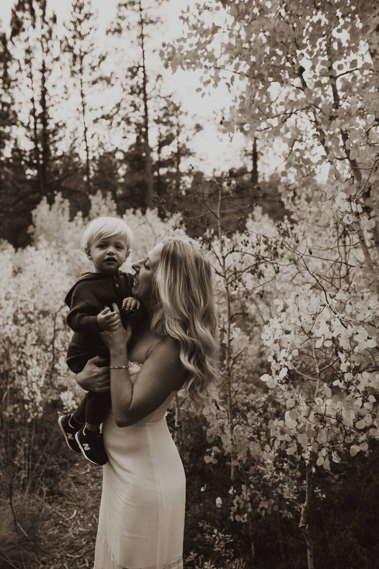 Joyful family interaction captured in sepia tones among aspen trees.