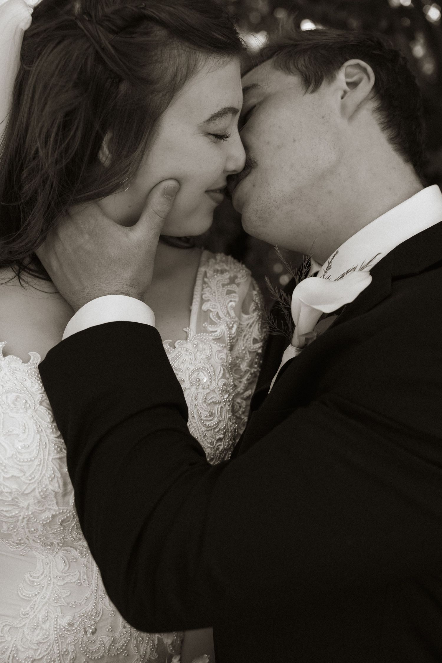 Black and white close-up of a bride and groom sharing a tender kiss on their wedding day.